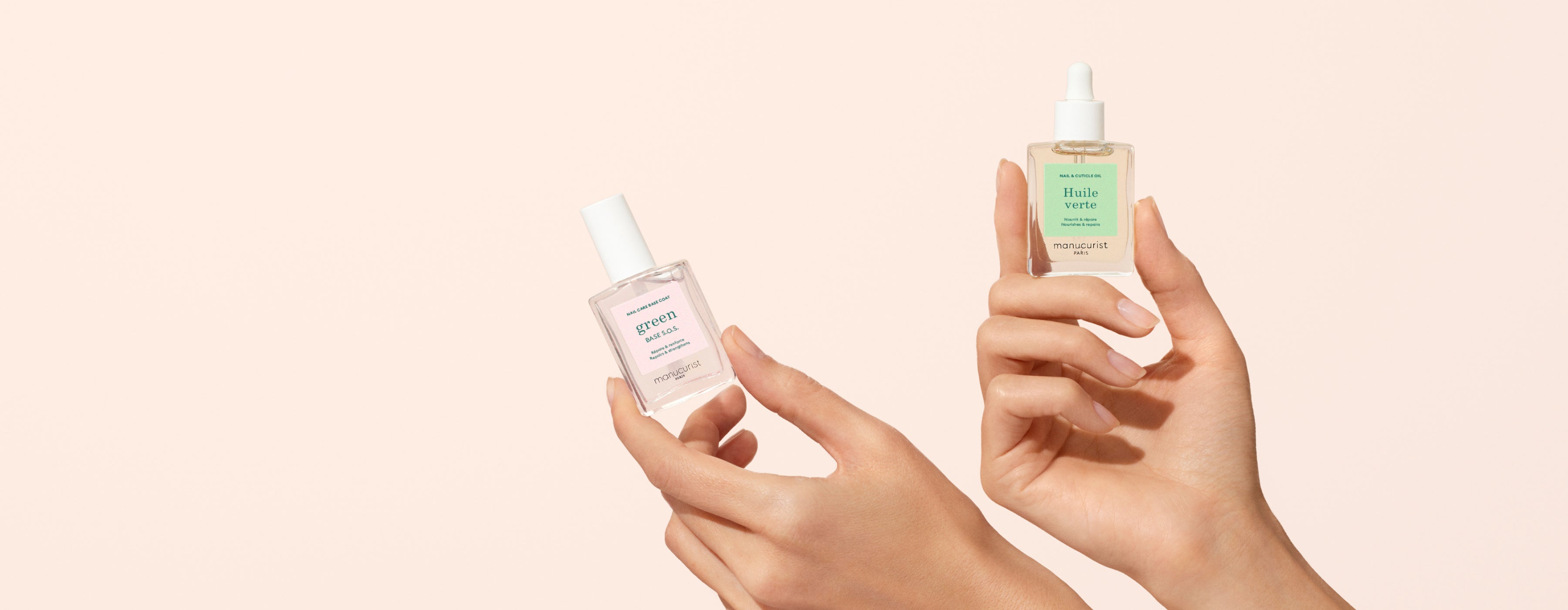 Two hands are holding clear glass skincare bottles with white caps and pastel green labels against a soft beige background. One bottle has a dropper top, the other has a screw cap.