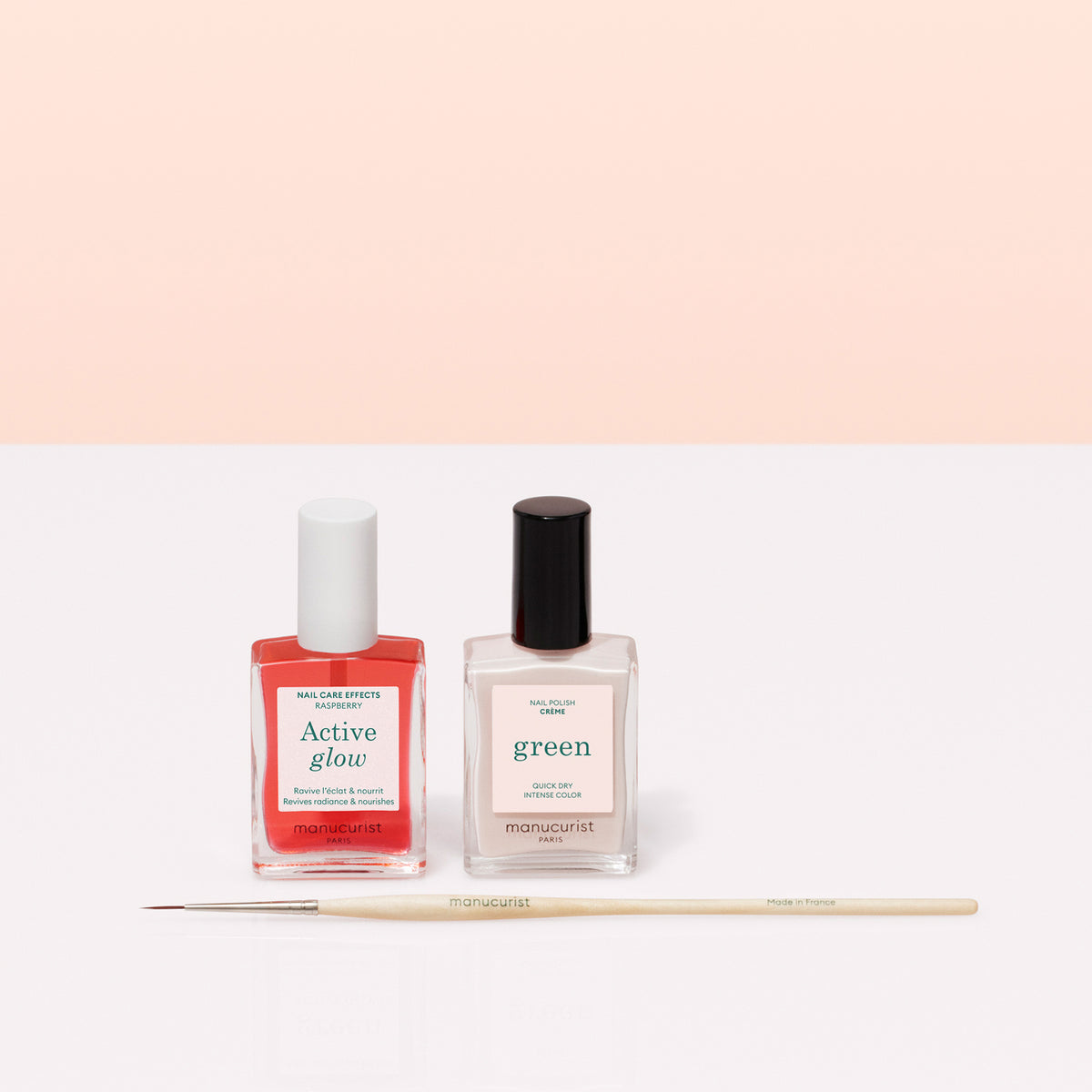 Deux flacons de vernis Manucurist French Manicure Glow sont côte à côte avec un pinceau fin de Nail Art devant, sur un fond rose clair — idéal pour créer une brillance effet gel et la French manucure parfaite.