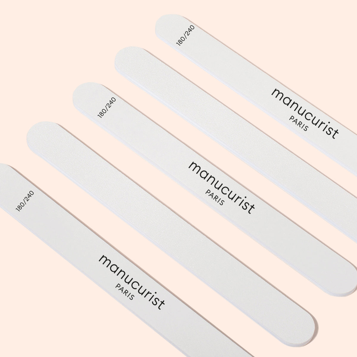 Cinq limes émeri Manucurist-us 180/240 pour ongles fragiles sont disposées en diagonale sur un fond beige clair, idéales pour façonner délicatement les ongles cassants ou sensibles.
