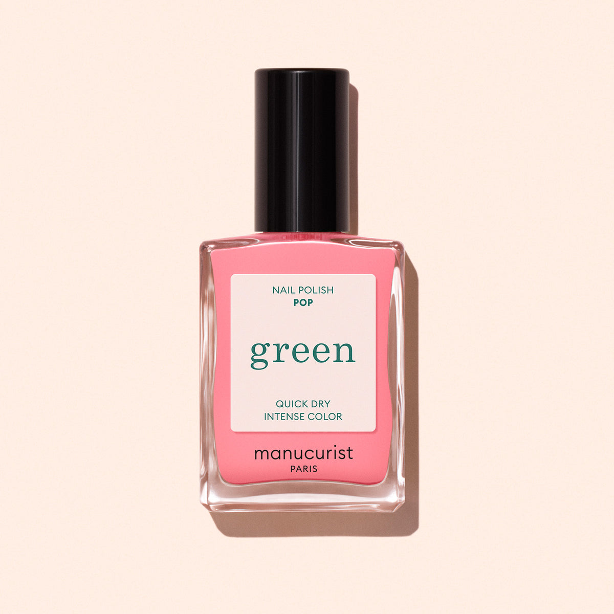 Un flacon de vernis à ongles Manucurist Pop de la gamme Green™, avec un bouchon noir, est posé sur un fond beige clair. L’étiquette indique séchage rapide et couleur intense.