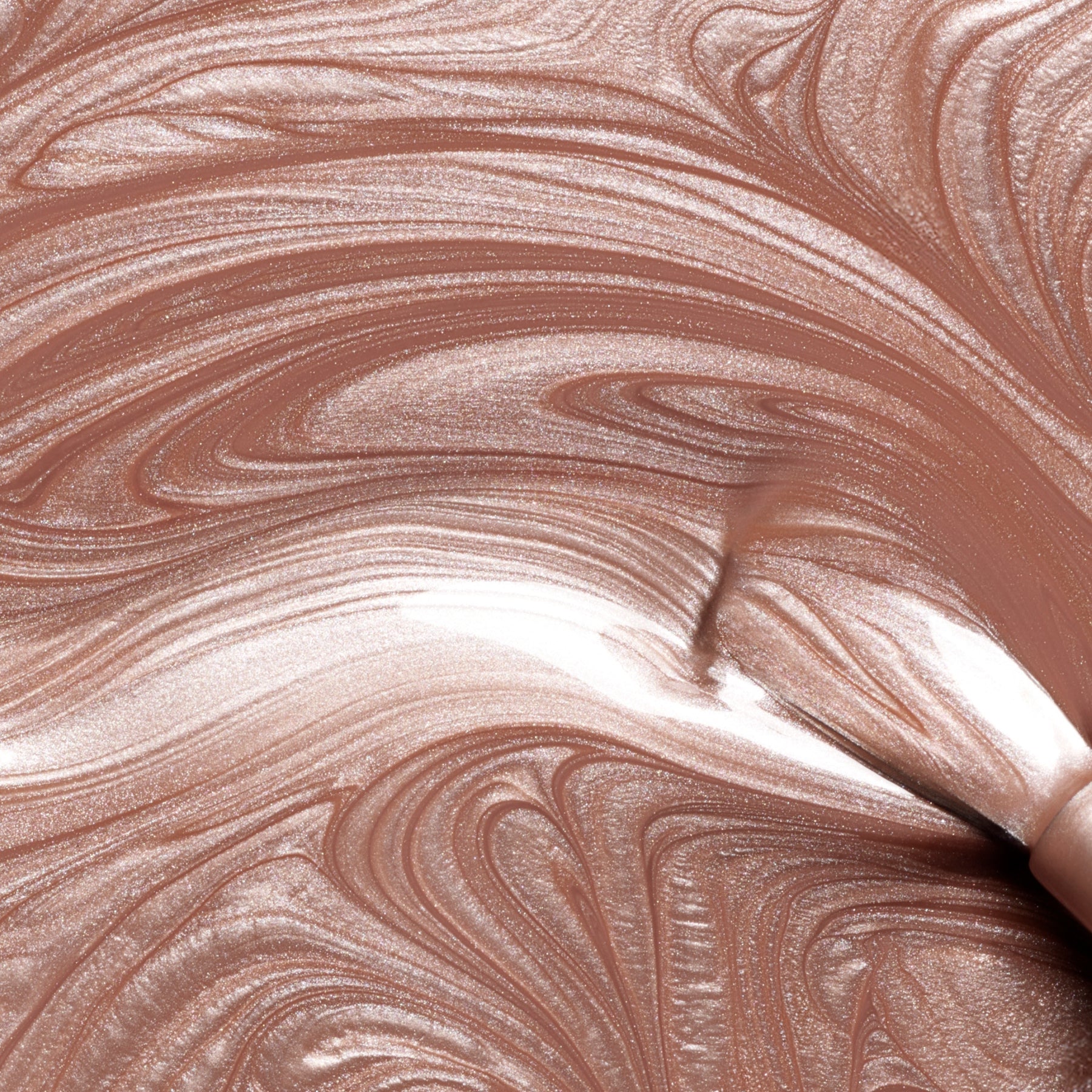Sandstone by Manucurist is a metallic rose gold liquid featuring swirling patterns and shimmery highlights, resulting in an abstract and glossy texture reminiscent of pearly brown nail polish.