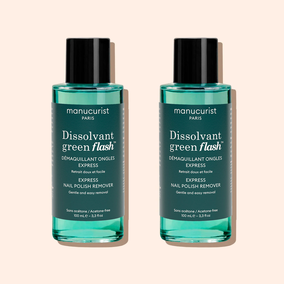 Deux flacons identiques de Manucurist Green Flash™ Gel Polish Remover contenant un liquide bleu sarcelle, avec des bouchons noirs et des étiquettes blanches, sont placés côte à côte sur un fond beige.