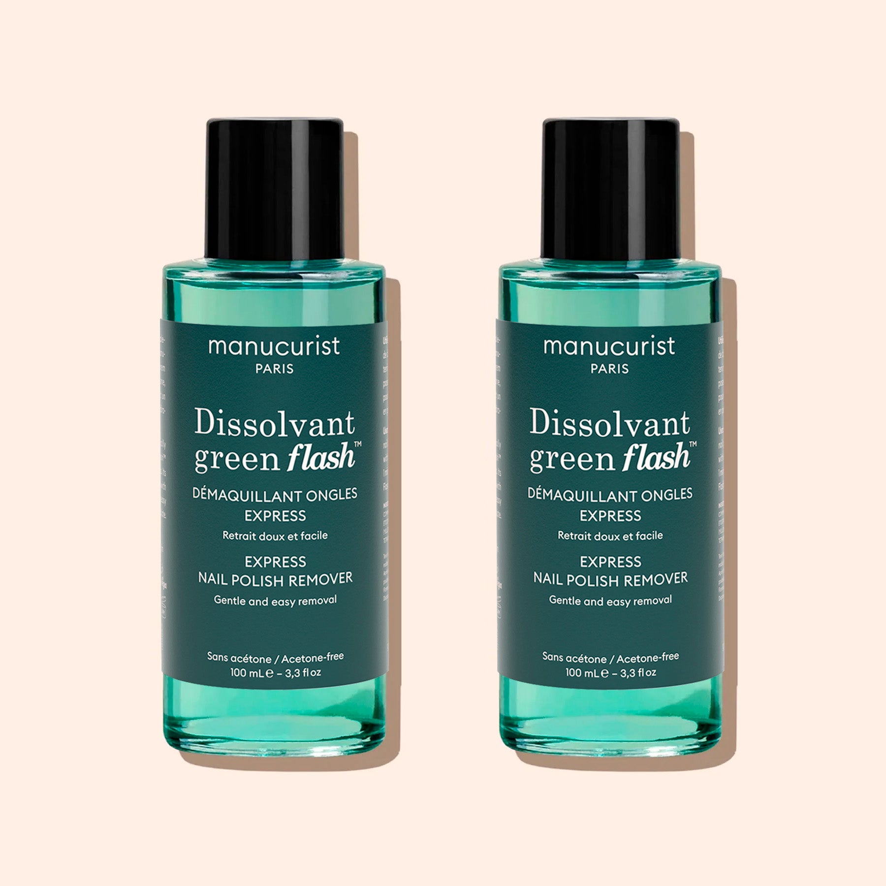 Two identical bottles of Manucurist Green Flash™ Gel Polish Remover with teal liquid, black caps, and white labels stand side by side on a beige background.