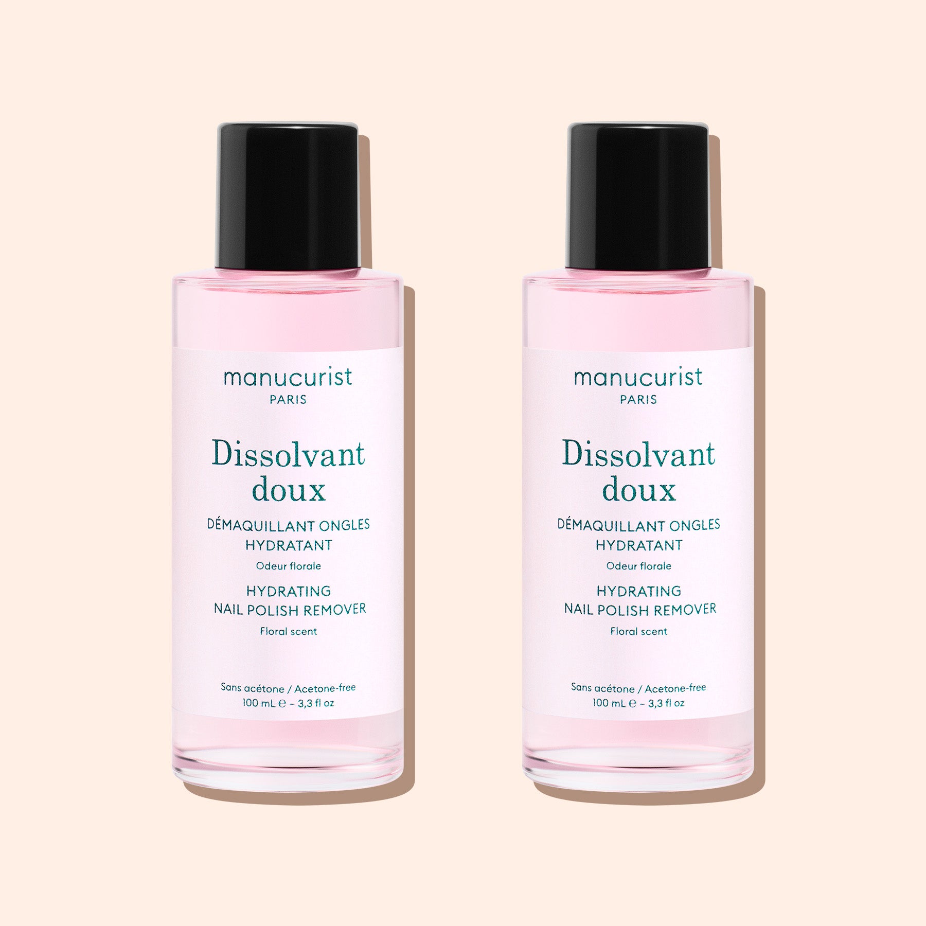 Two bottles of Manucurist Gentle Remover, featuring pale pink, acetone-free liquid with black caps and white labels, are placed side by side on a light beige background.