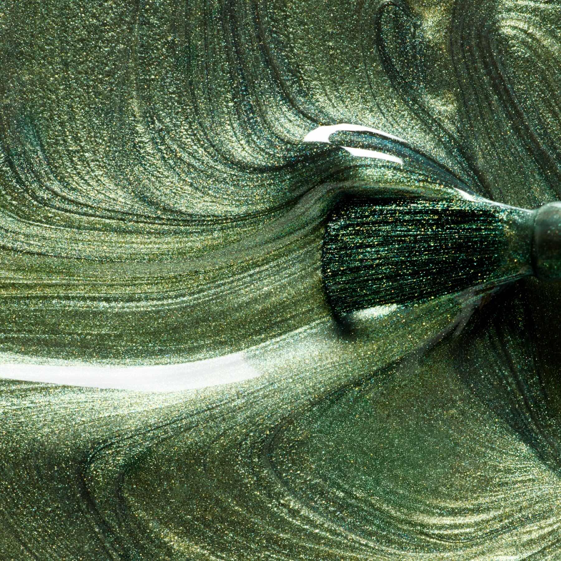 A close-up shows a brush applying Manucurist’s Groove metallic green gel polish, creating glossy, swirling patterns and vibrant, metallic textures on the surface.