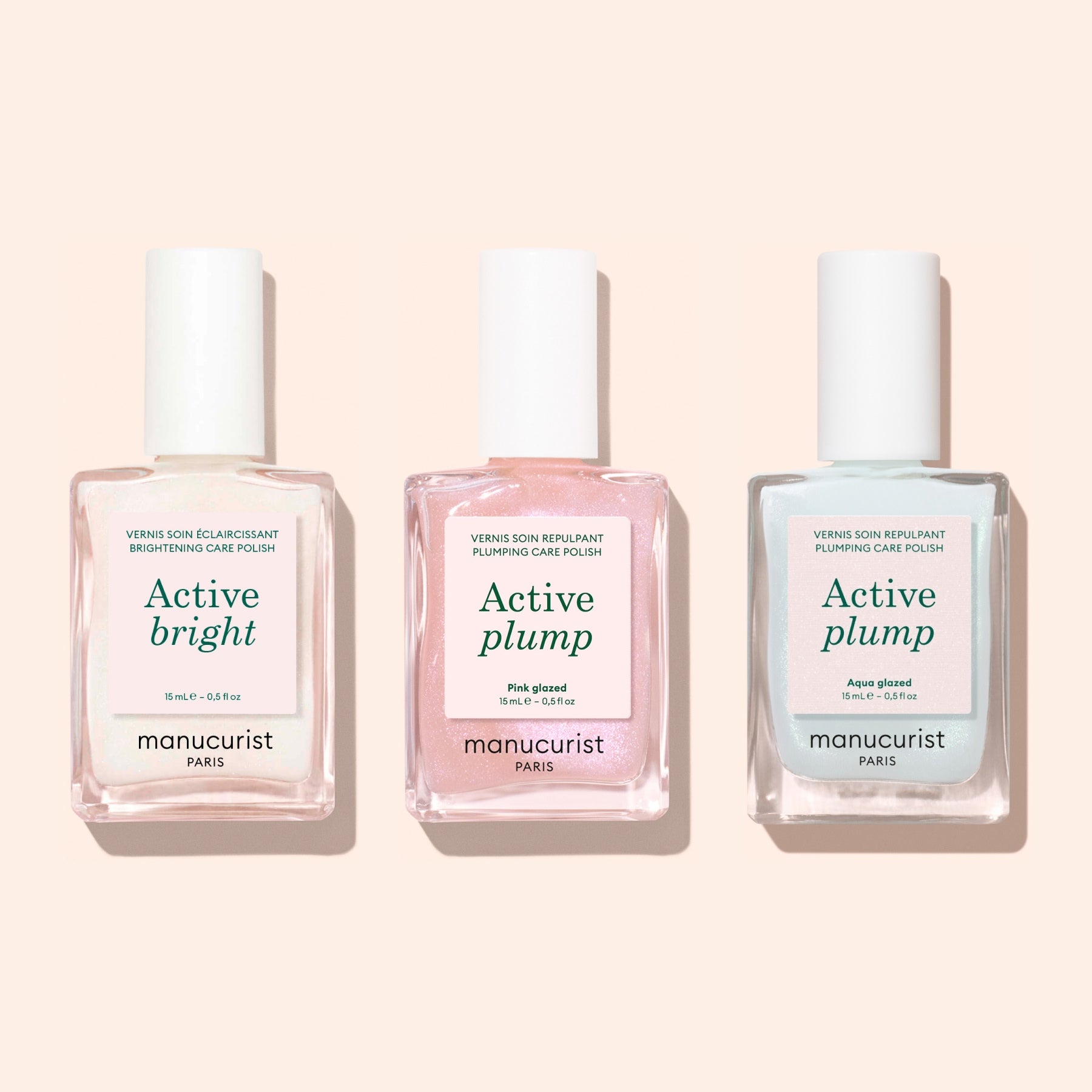 Three bottles of Manucurist nail polish—Active Bright, Active Plump Pink Glow, and Active Plump Aqua Glazed—stand against a light pink background, delivering hydrated nails with a subtle pearly finish.