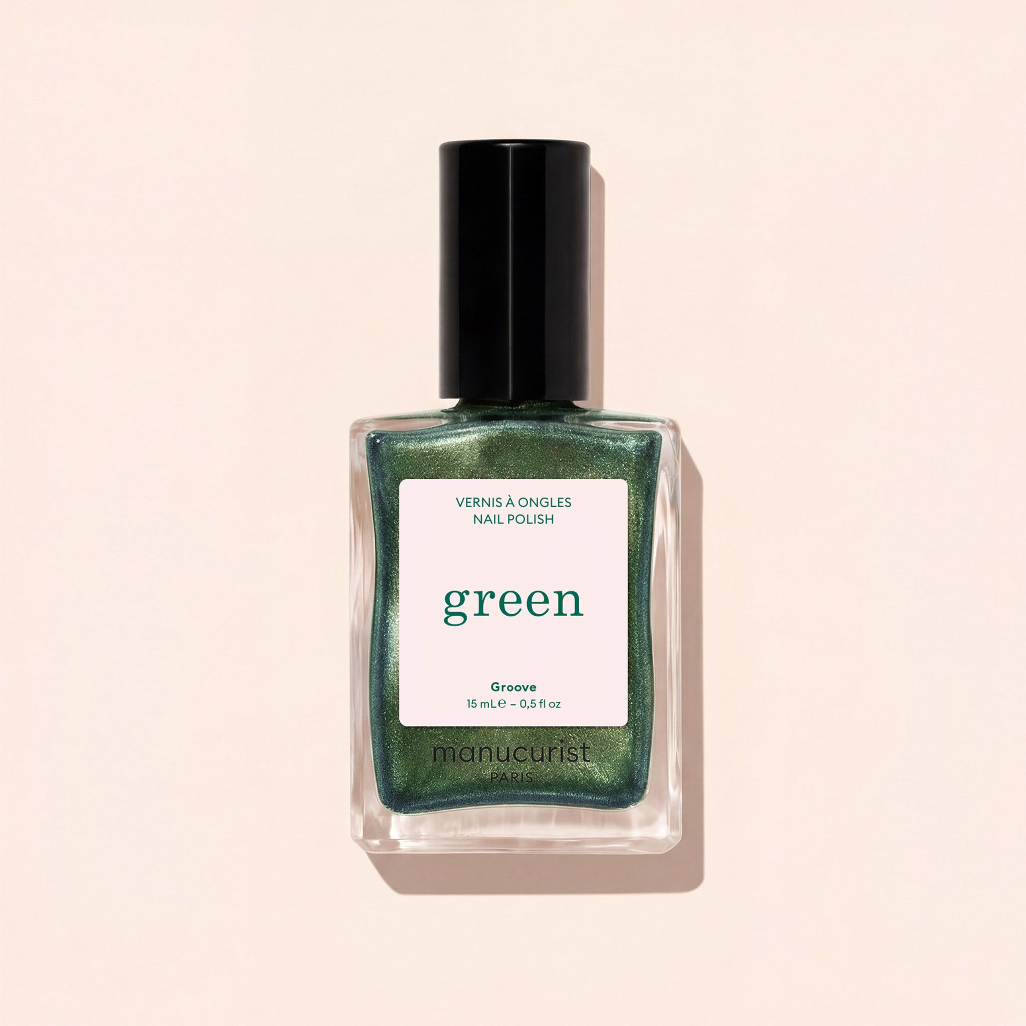 A glass bottle of pearly green nail polish with a black cap is shown against a light beige background. The label reads Groove by Manucurist.