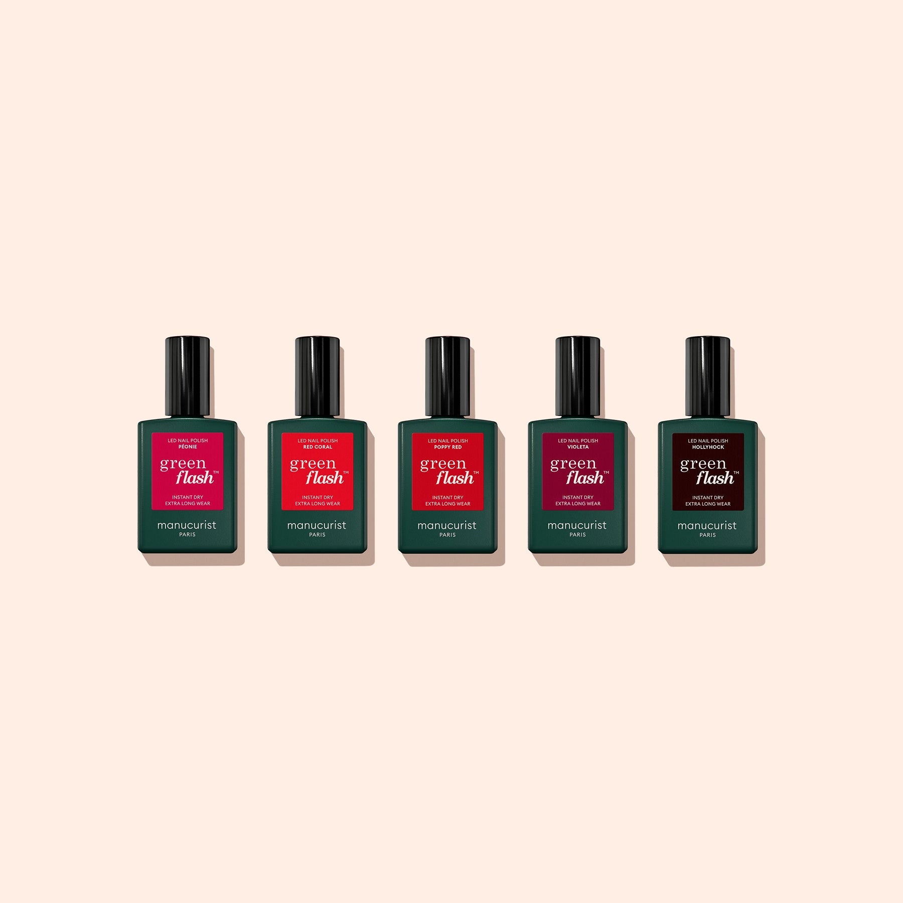 Five bottles from the Manucurist Customizable 5-pack are arranged in a row against a light beige background, each featuring a different red or pink label.
