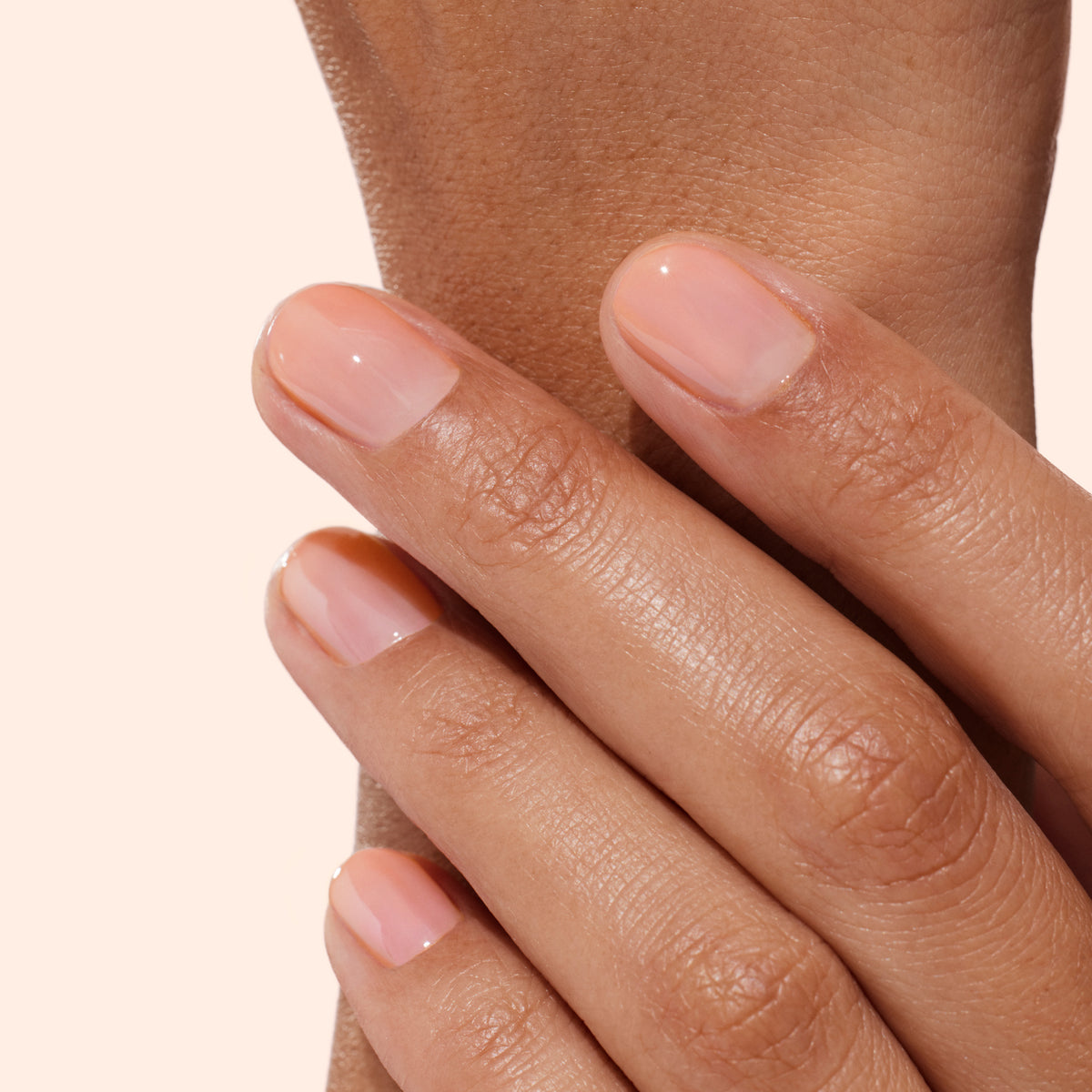Un gros plan sur des ongles parfaitement manucurés révèle un look nude naturel et brillant obtenu avec le Strong Glow Trio de Manucurist, un coffret conçu pour réparer et renforcer les ongles abîmés, pour une apparence saine et une forme impeccable.