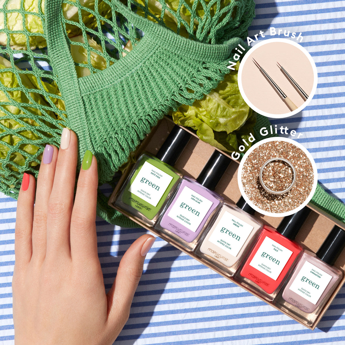 Une main aux ongles multicolores repose sur un tissu rayé à côté de cinq flacons de vernis à ongles Manucurist « Glitter in Love » à étiquette verte, de paillettes biodégradables, de pinceaux fins pour Nail Art et d&