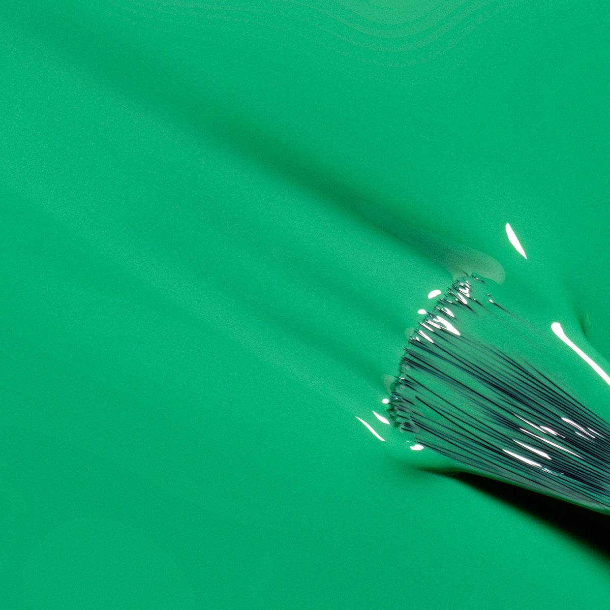 Gros plan d’un pinceau appliquant le vernis vert électrique Brazil de Manucurist, avec des poils visibles et un Top Coat brillant apportant éclat et profondeur à la finition semi-mate.
