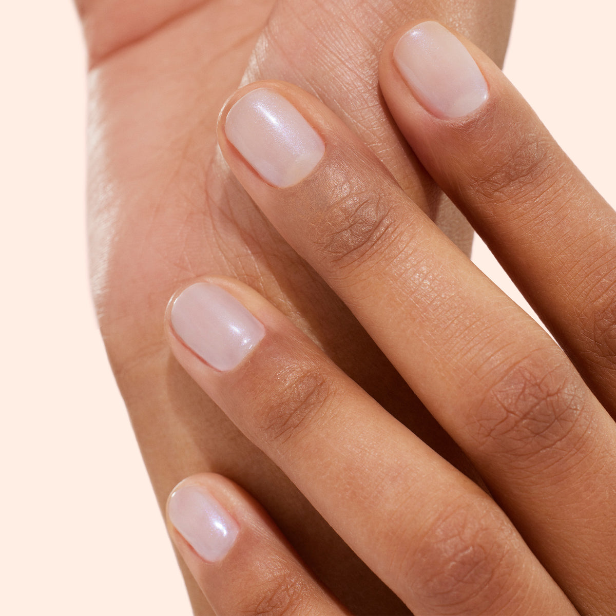 Gros plan sur une main aux ongles soignés vernis avec Active™ Bright de Manucurist, un vernis biosourcé diaphane à la teinte naturelle, délicatement posée sur l&