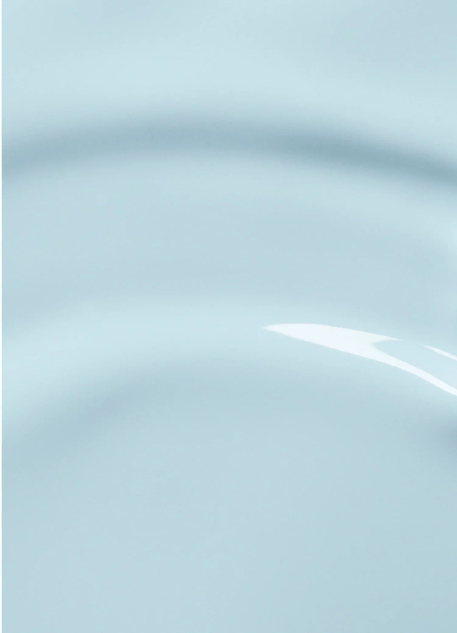 Close-up of a smooth, light blue surface with subtle curved ridges and a glossy reflection, creating an abstract, minimalist appearance.