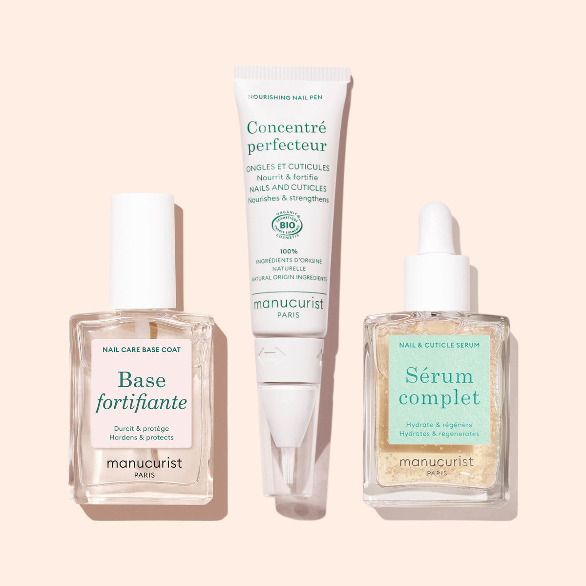 Trois produits Manucurist sur un fond rose clair : Force Nail Hardener dans un flacon carré, un sérum pour les ongles et les cuticules avec compte-gouttes, et un stylo nourrissant pour les ongles en tube.