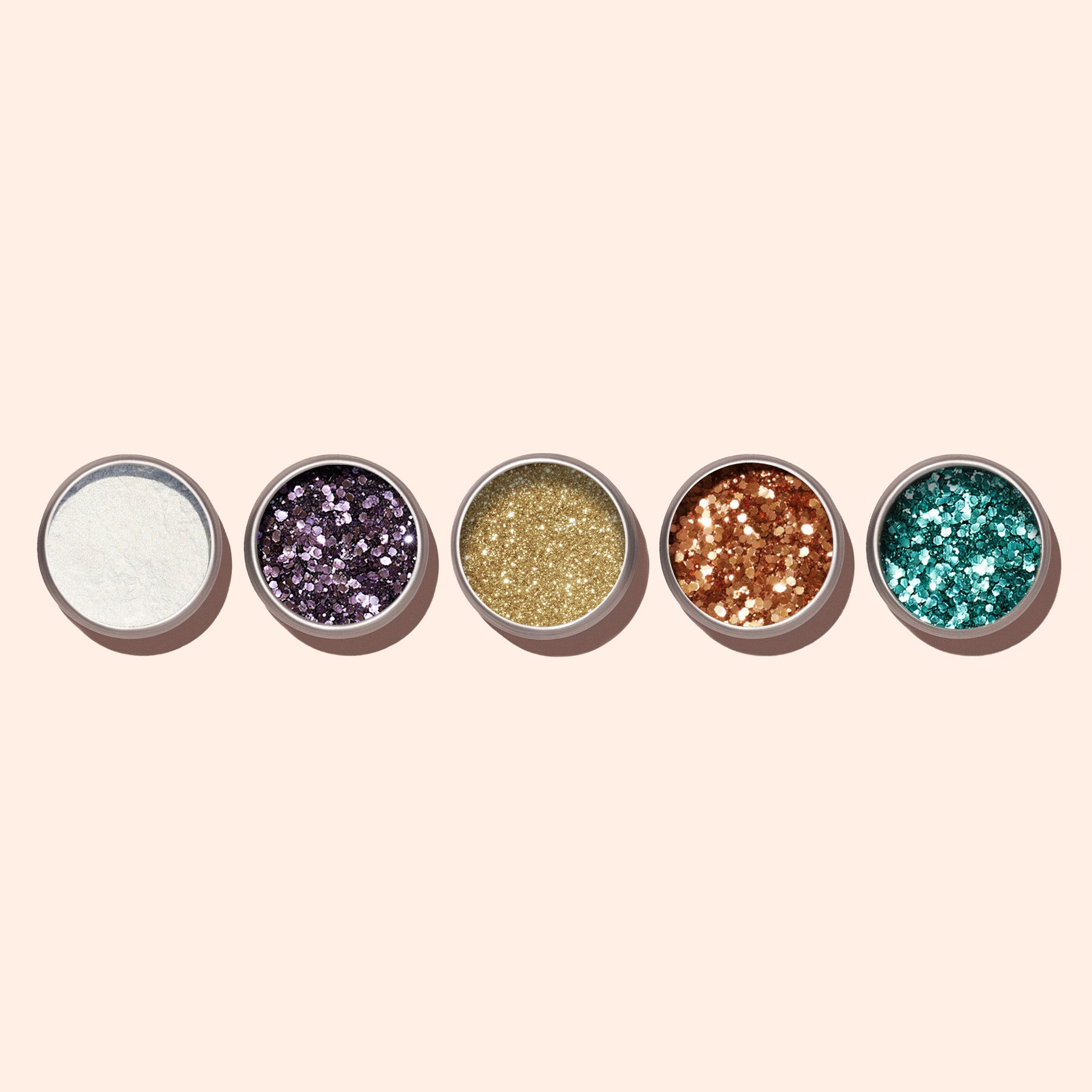 Five small round containers of Manucurist Turquoise Biodegradable Glitter in white, purple, gold, copper, and teal shades—ideal for gel polish or creative nail art—are arranged in a row on a light beige background.