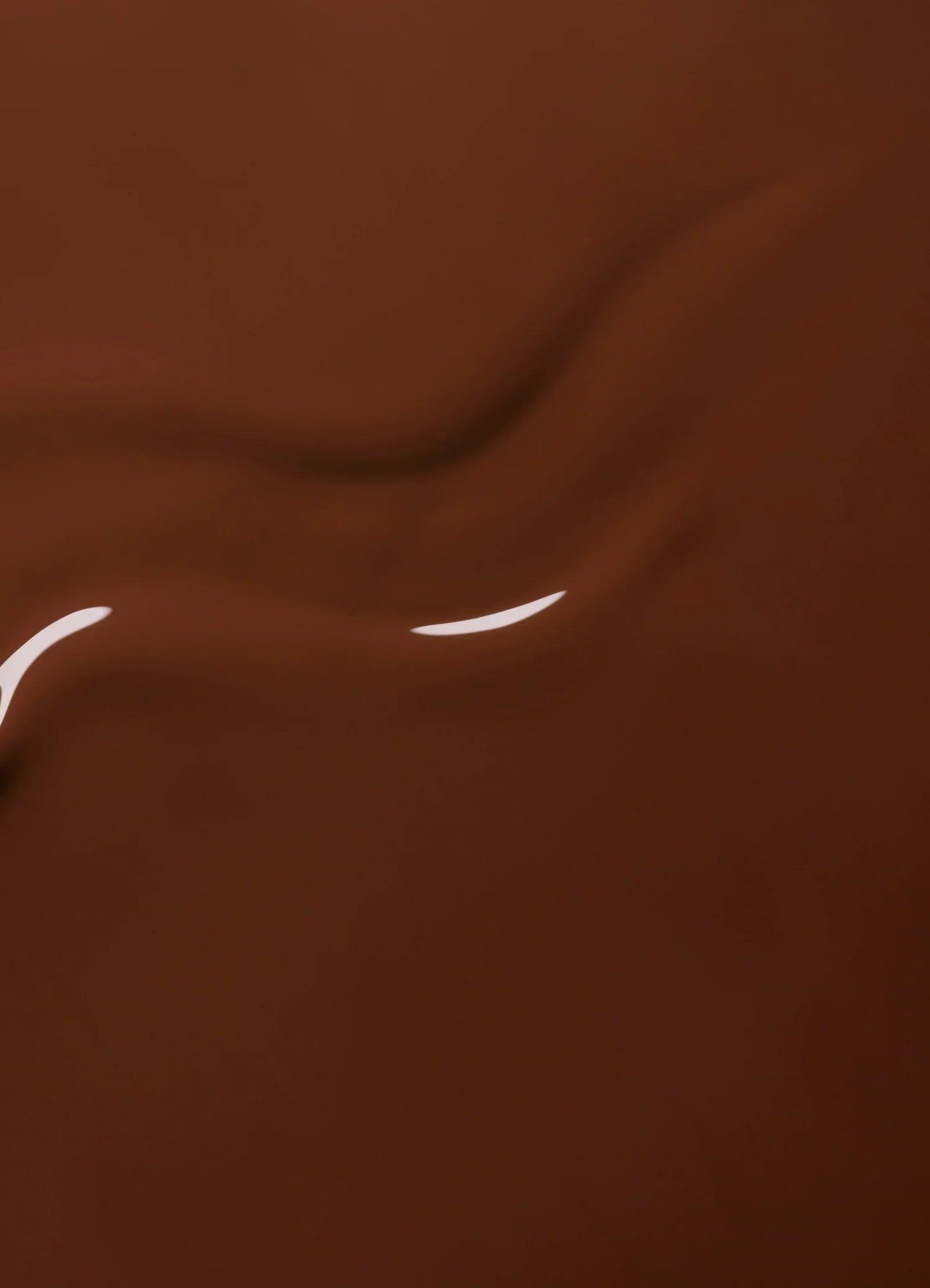 Smooth, rich brown liquid chocolate with glossy highlights and gentle swirling patterns creating a silky, appetizing texture.