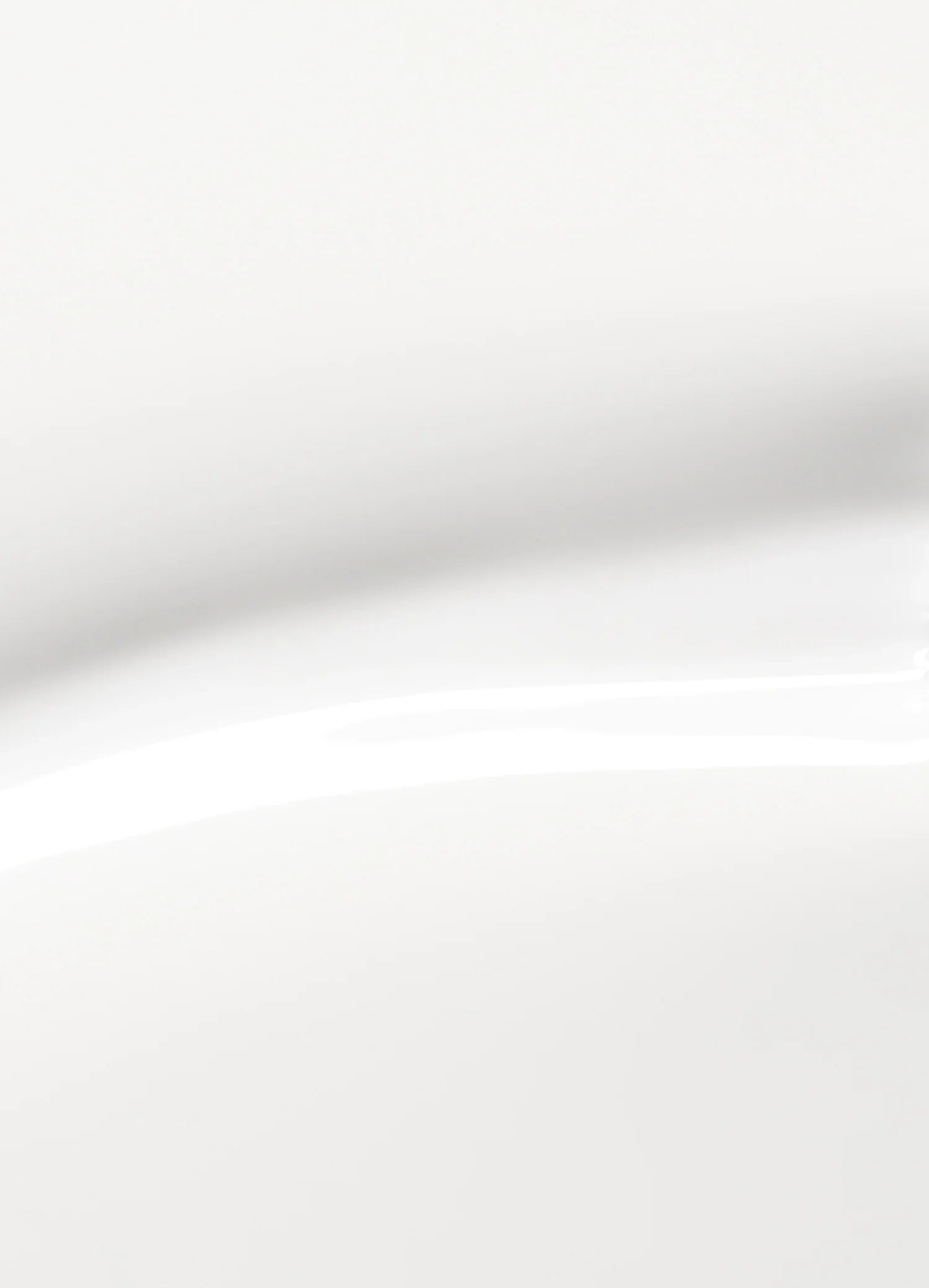 A close-up of a smooth, white, glossy surface with soft shadows and gentle curves, creating an abstract and minimalist appearance.