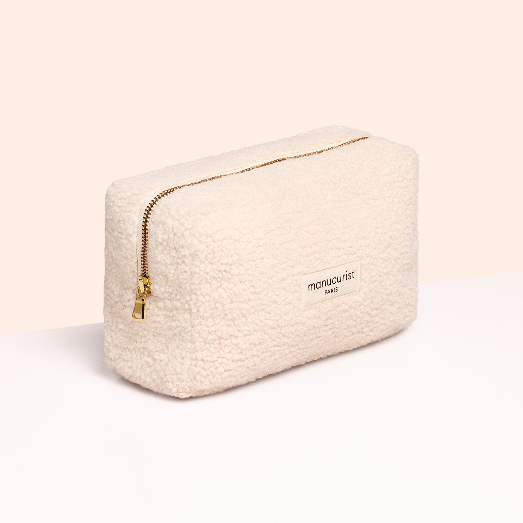 A rectangular, cream-colored textured pouch with a gold zipper and a small Manucurist label, perfect for storing your Super Starter Kit by Manucurist, shown against a pale background.
