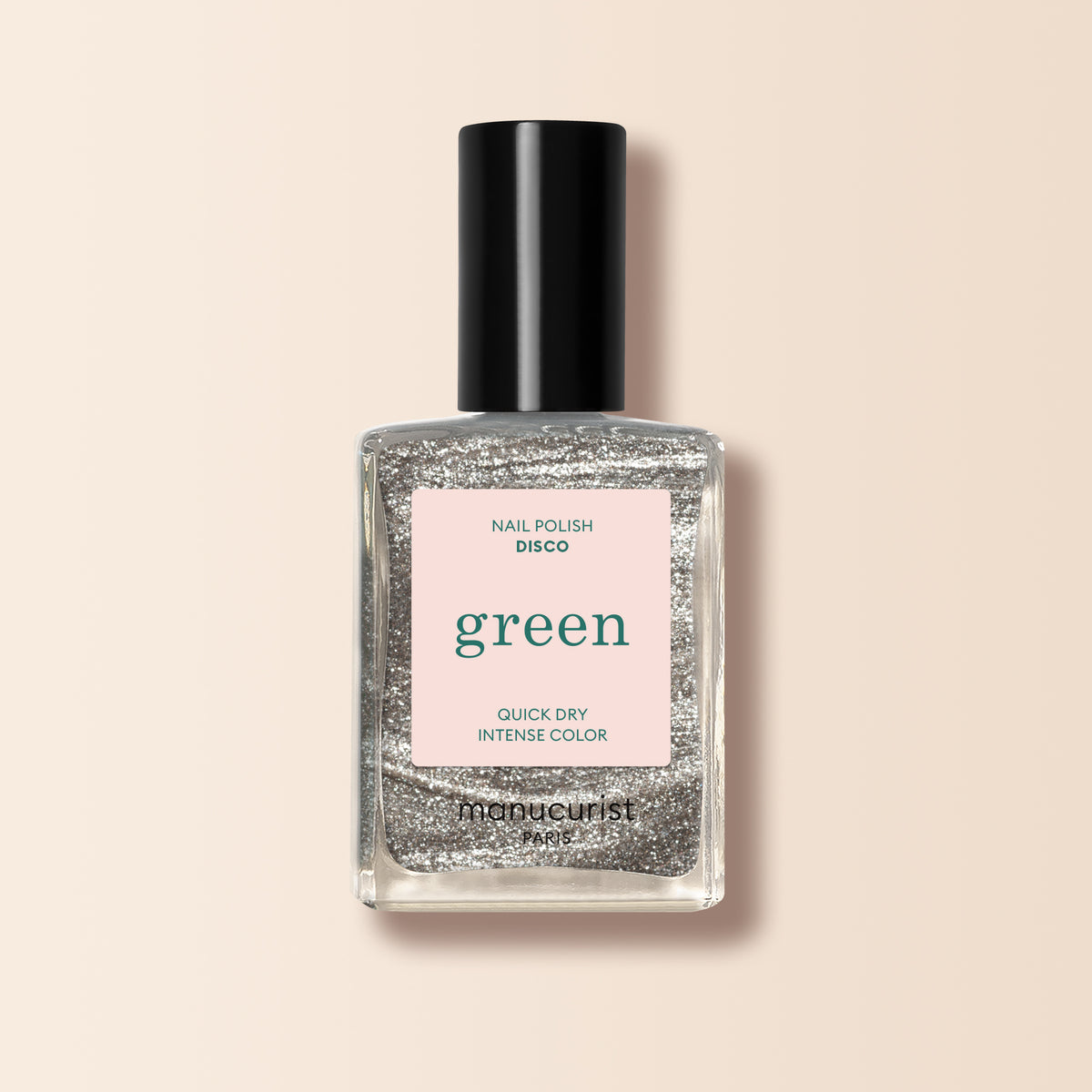 Un flacon en verre transparent de vernis à ongles pailleté argenté Disco de Manucurist de la gamme Green™, portant les mentions green et quick dry intense color, se tient debout sur un fond beige clair.