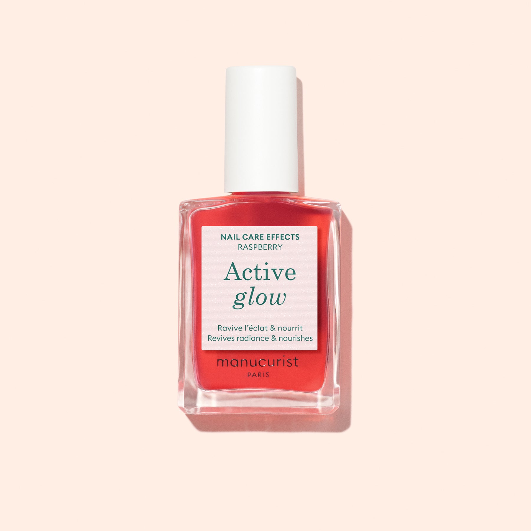 Manucurist Active Glow Raspberry, a plant-based nail enhancer, is displayed in a clear bottle with a white cap and pink label, set against a pale pink background.