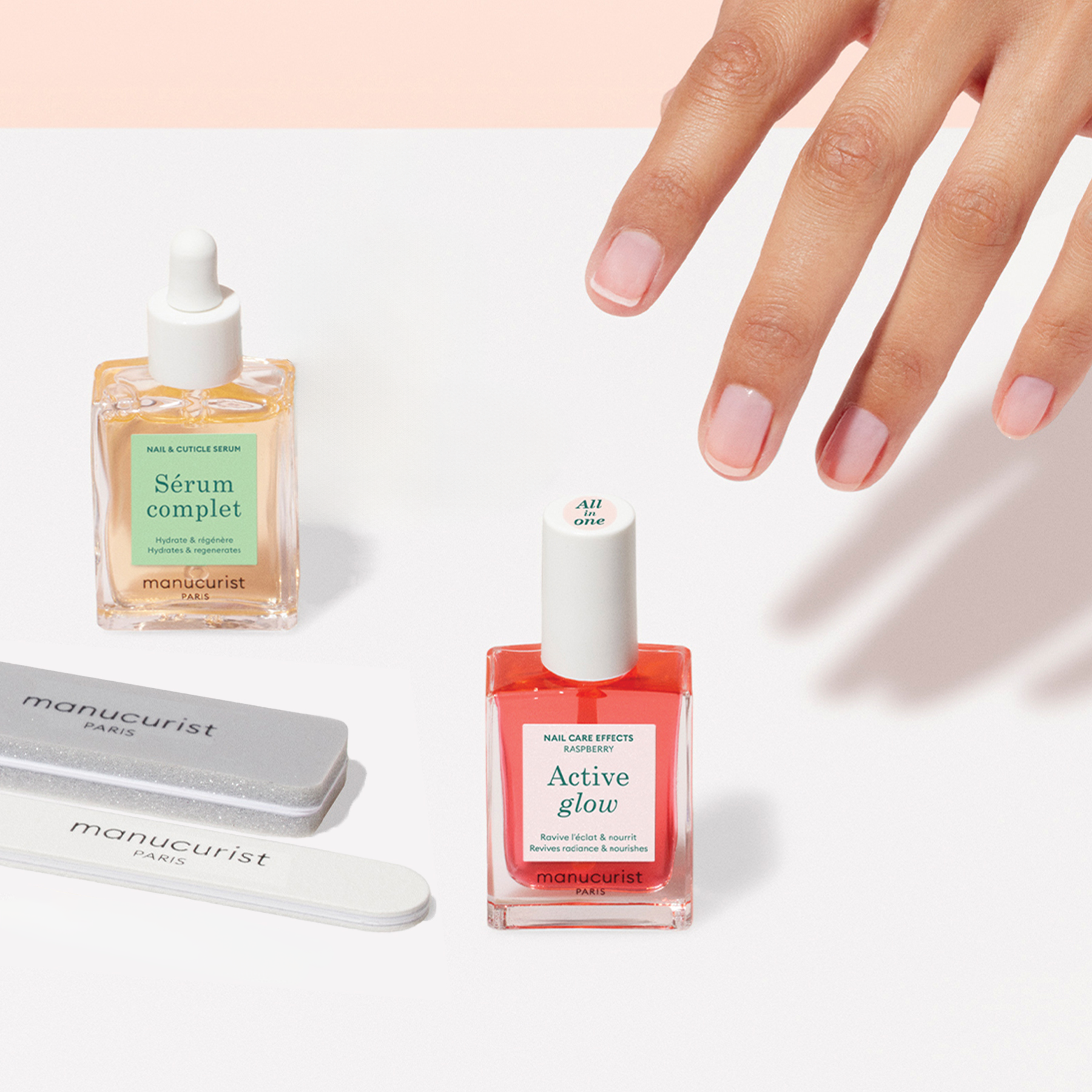 A manicured hand reaches for the Manucurist US Active Discovery Kit—featuring “Sérum complet,” “Active Glow,” and two nail files—essentials on a light surface for a flawless, hydrated manicure.