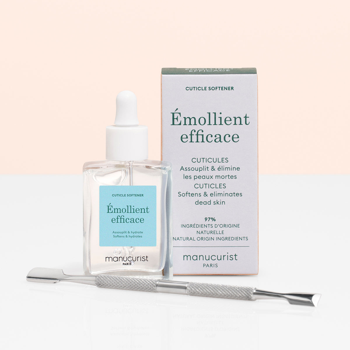 Un flacon en verre de Manucurist Cuticle Softener Pusher Duo avec un compte-gouttes, sa boîte et un repoussoir en métal sur une surface blanche sur fond rose clair — idéal pour ramollir et retirer délicatement la peau morte autour de la surface de l&