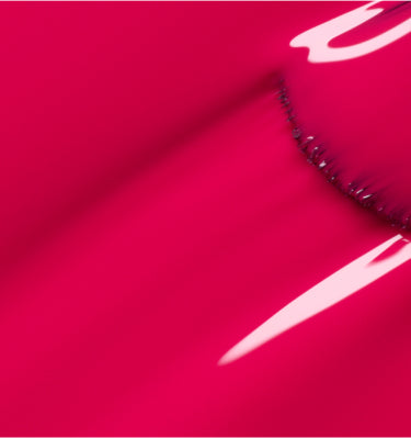 Gros plan sur une surface rose vif et brillante aux courbes lisses et aux reflets lumineux, créant un aspect abstrait et glossy.