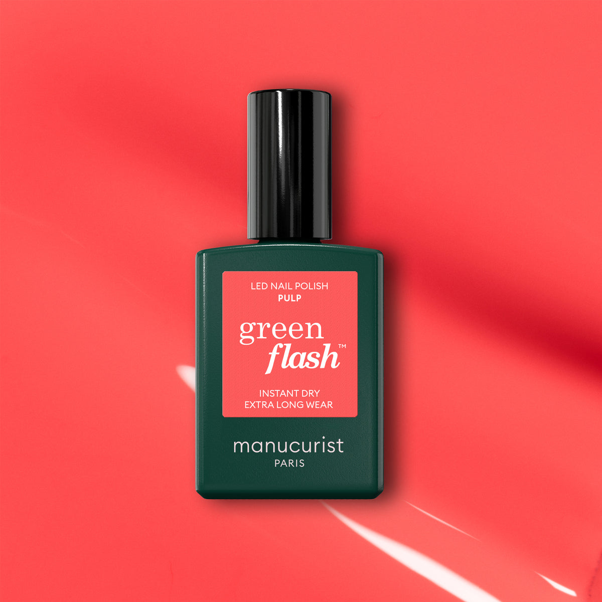 Un flacon de vernis gel Manucurist Pulp est présenté sur un fond rose corail avec des reflets lumineux. L&