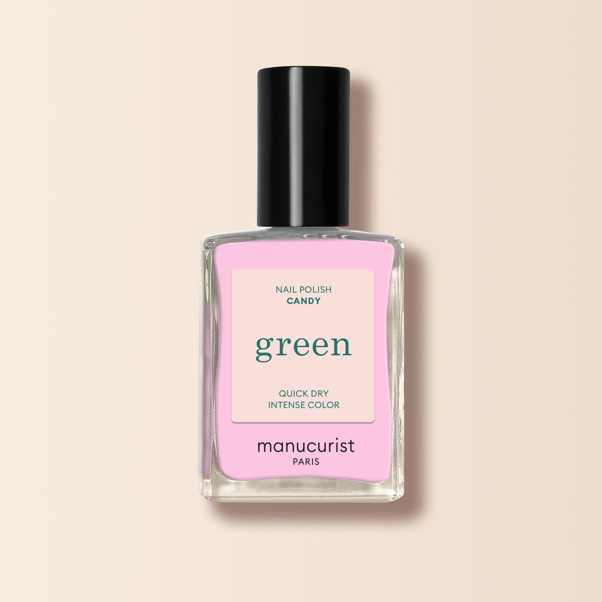 Un flacon de vernis à ongles Candy de Manucurist, avec un bouchon noir et une étiquette rose, est posé sur un fond beige clair doux.