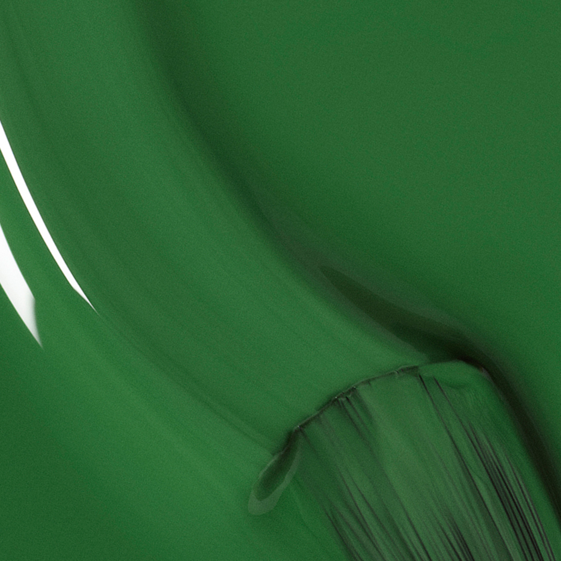 A close-up of a thick brushstroke of glossy green paint on a smooth surface, with visible bristle marks and highlights reflecting light.