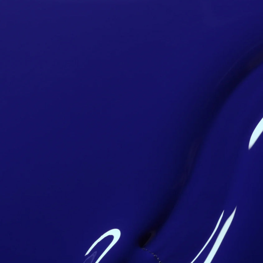 A close-up of a glossy, deep blue curved surface with a few white light reflections and smooth, flowing lines.