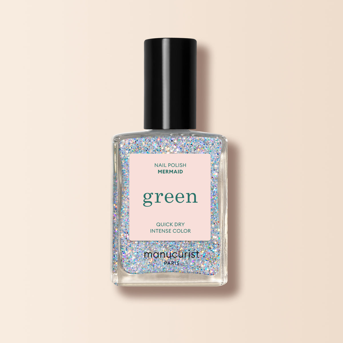 A bottle of Manucurist nail polish in the shade Mermaid with a black cap and clear base filled with iridescent glitter is displayed against a pale beige background.
