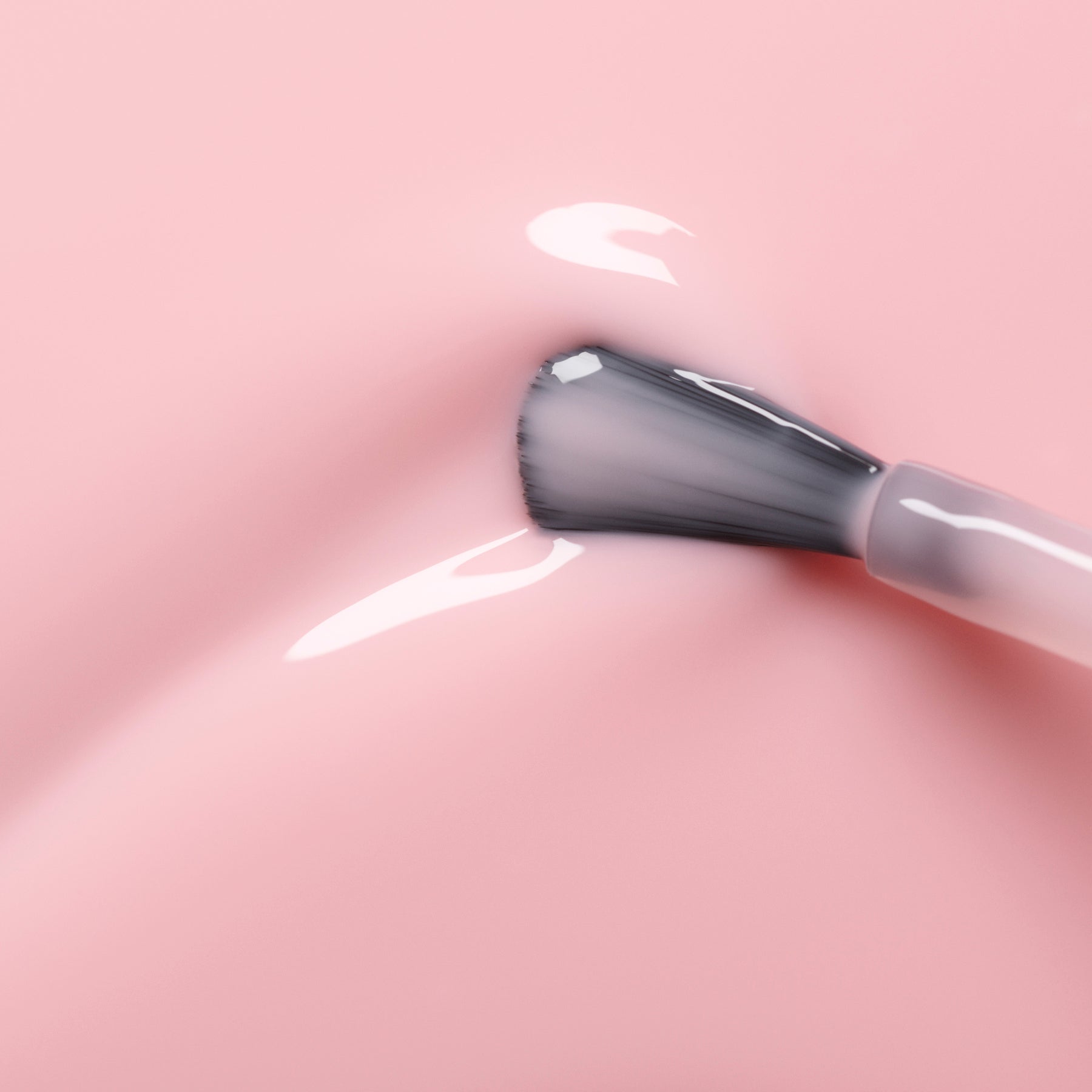 A close-up of a brush applying glossy light pink nail polish on a smooth, shiny surface, creating a soft and even coat.