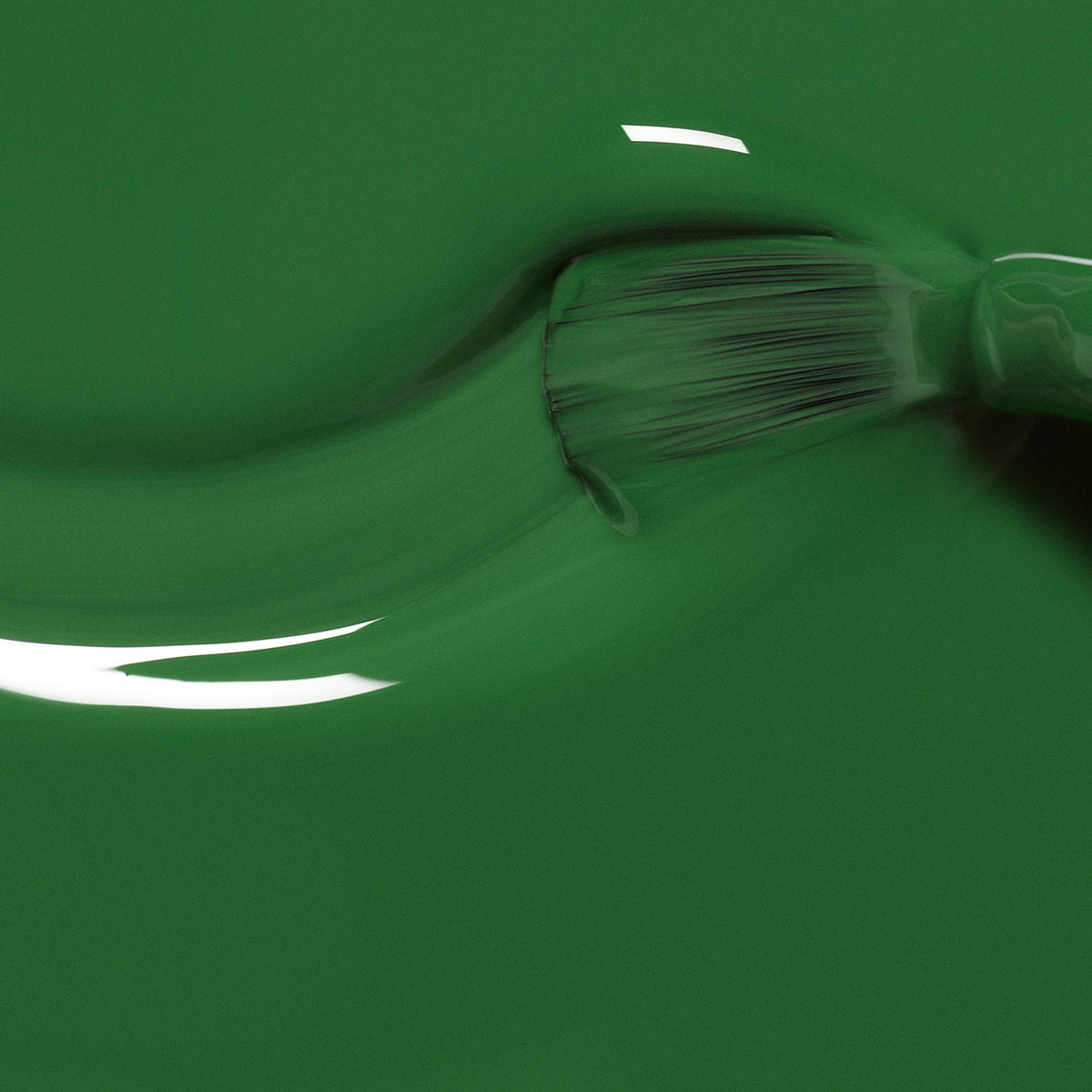 Gros plan d’un pinceau appliquant Manucurist Jade, un vernis vert minéral brillant, sur une surface lisse, avec des poils de pinceau visibles et des reflets brillants sur la finition humide.