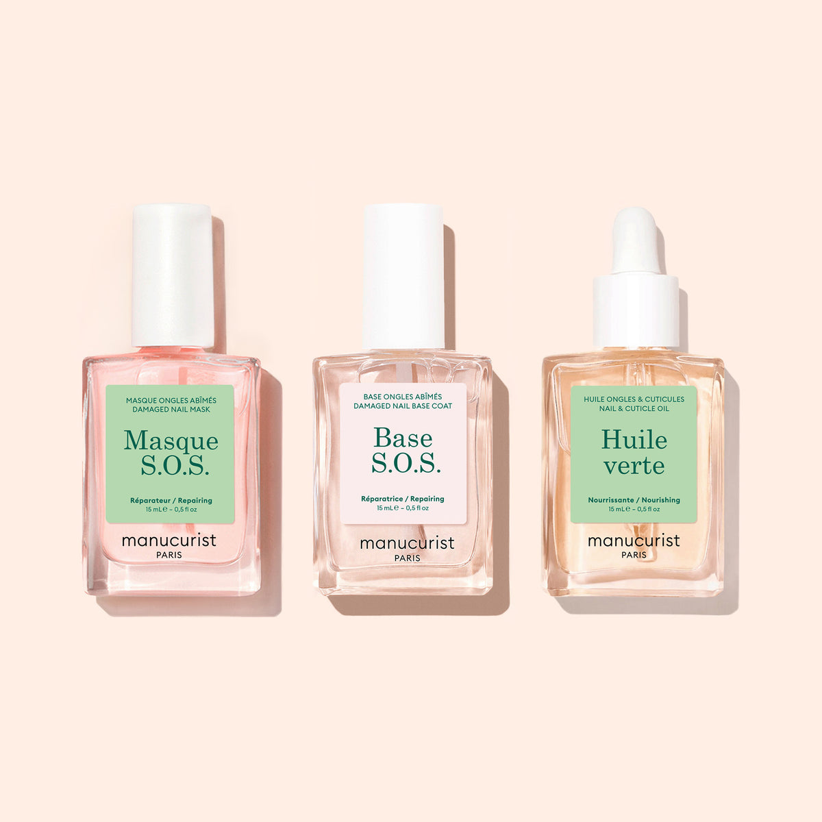 Three clear glass bottles with white tops, labeled S.O.S. Nail Mask by Manucurist, are arranged side by side on a light beige background.
