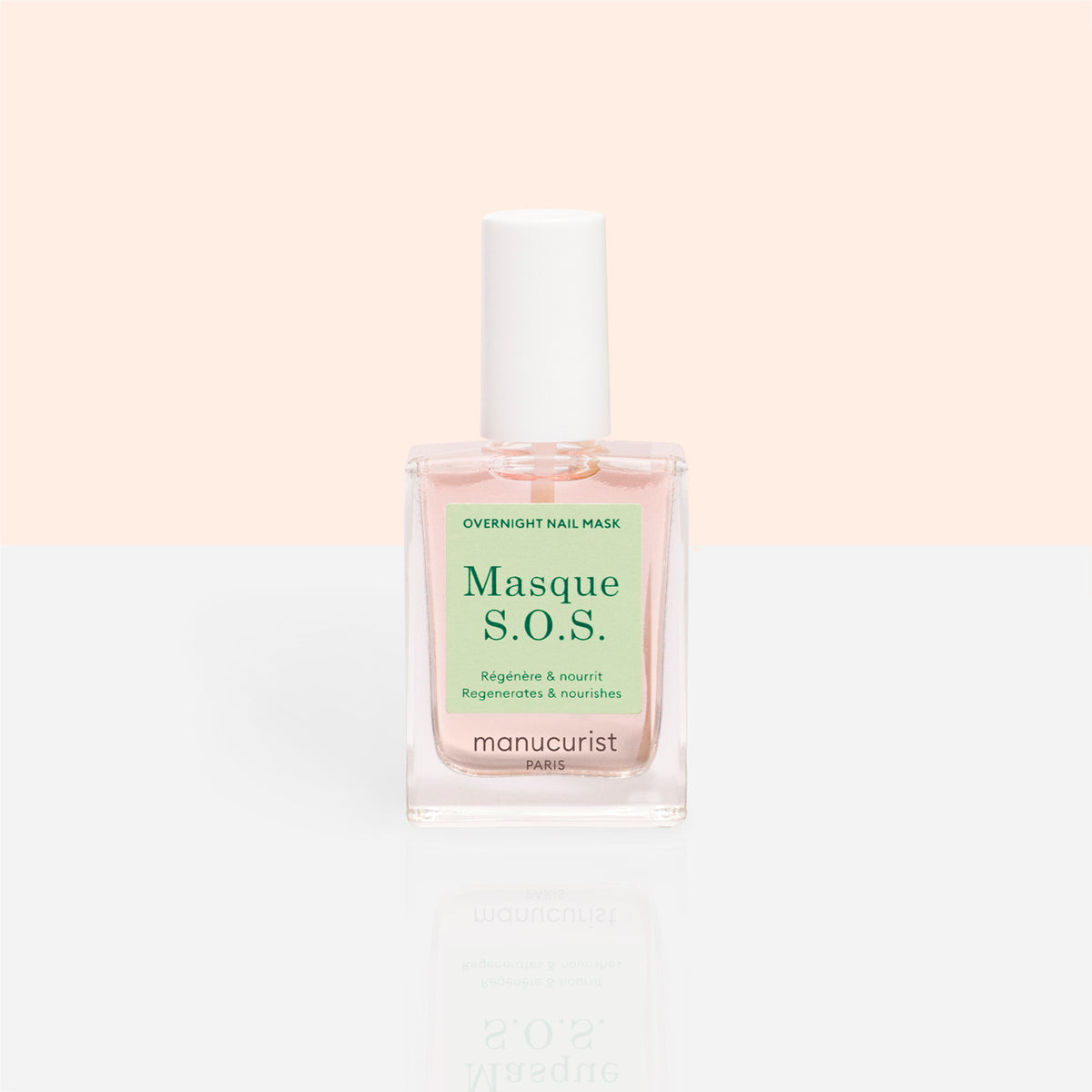Un flacon en verre transparent de Manucurist S.O.S. Nail Mask, un soin hydratant pour les ongles avec un bouchon blanc et un liquide rose pâle, posé sur un fond pêche pastel et blanc.