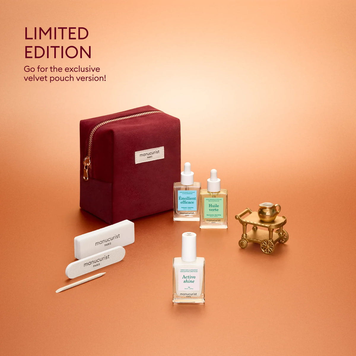 A burgundy velvet pouch, two Manucurist nail polish bottles, cuticle oil, a nail file, buffer, and a small gold cart are arranged on a gradient peach background. Text reads: LIMITED EDITION. Discover the exclusive Manucurist Active™ Discovery Gift Set—perfect as a holiday gift or to elevate your manicure routine for beautiful nails!.