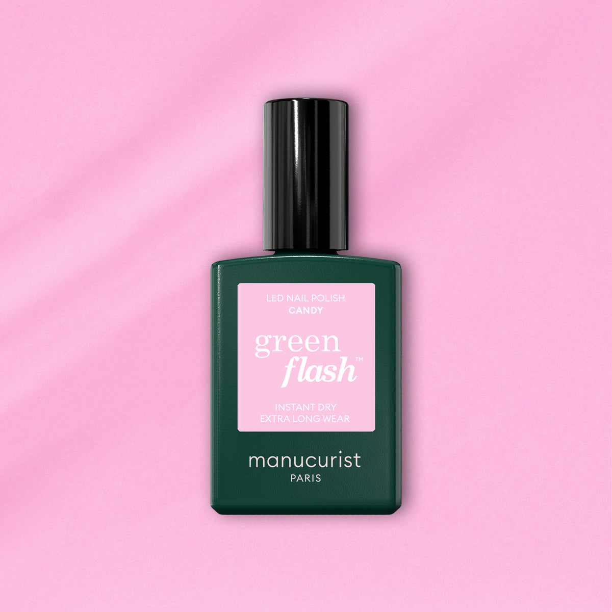 Un flacon de vernis à ongles LED Manucurist Candy Green Flash, avec un label rose et un corps vert foncé, posé sur un fond rose clair — idéal pour celles qui aiment les manucures LED aux teintes froides.