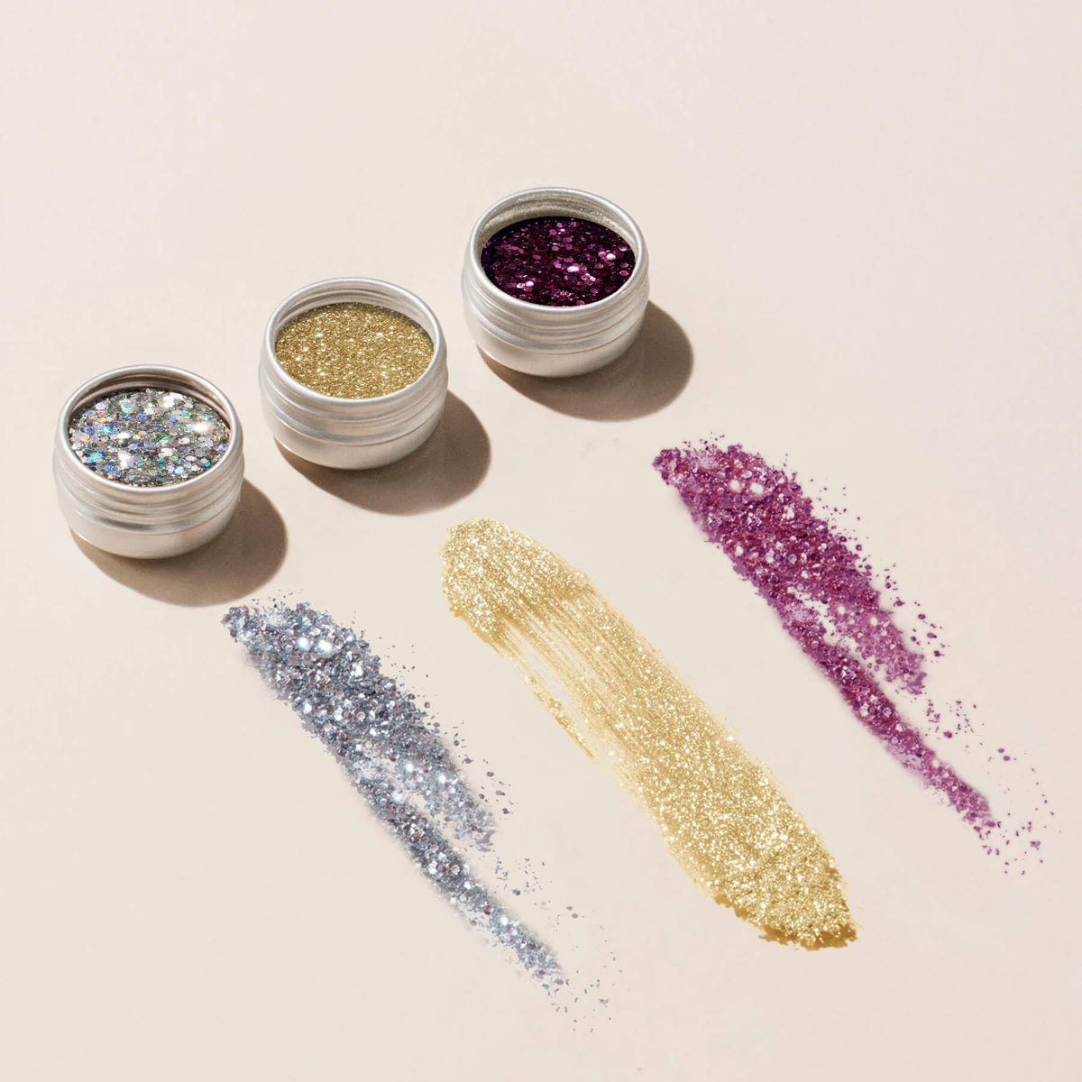 Trois pots ouverts du trio Paillettes et Poudres à Effets Manucurist — argenté, doré et violet — posés sur une surface claire, chacun avec un swatch intense au-dessous. Idéal pour apporter une touche scintillante à vos créations de Nail Art, en vernis classique ou semi-permanent.