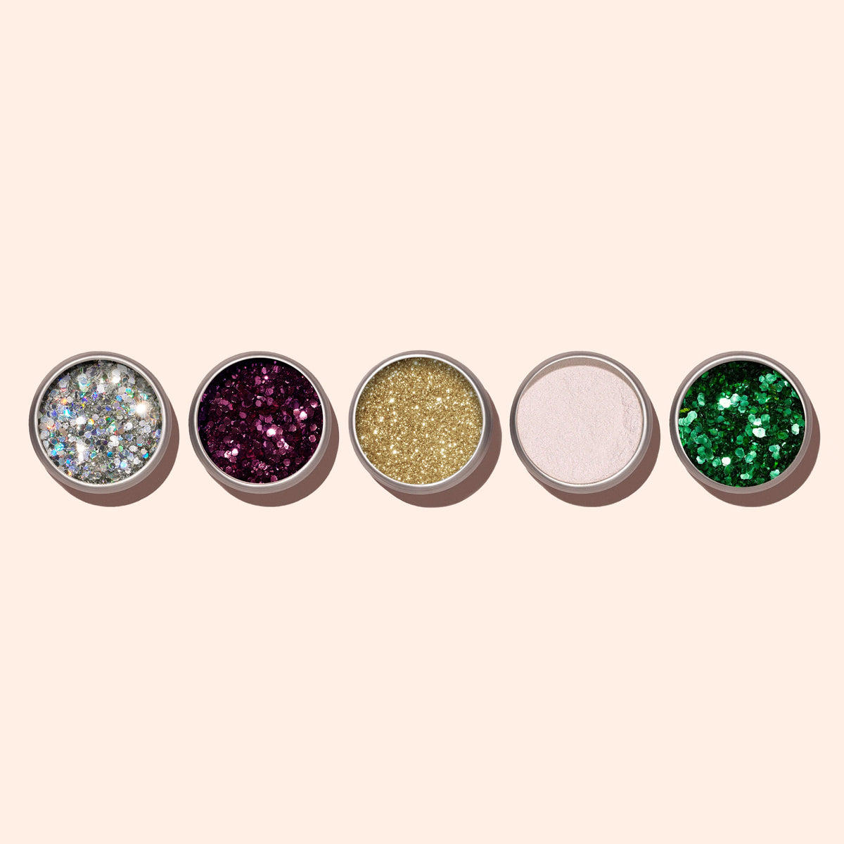 Cinq pots ronds de paillettes biodégradables Biodegradable Holo Glitter de Manucurist — argent, violet, or, rose pâle et vert — contenant des poudres scintillantes pour un Nail Art créatif, soigneusement disposés sur un fond beige clair.
