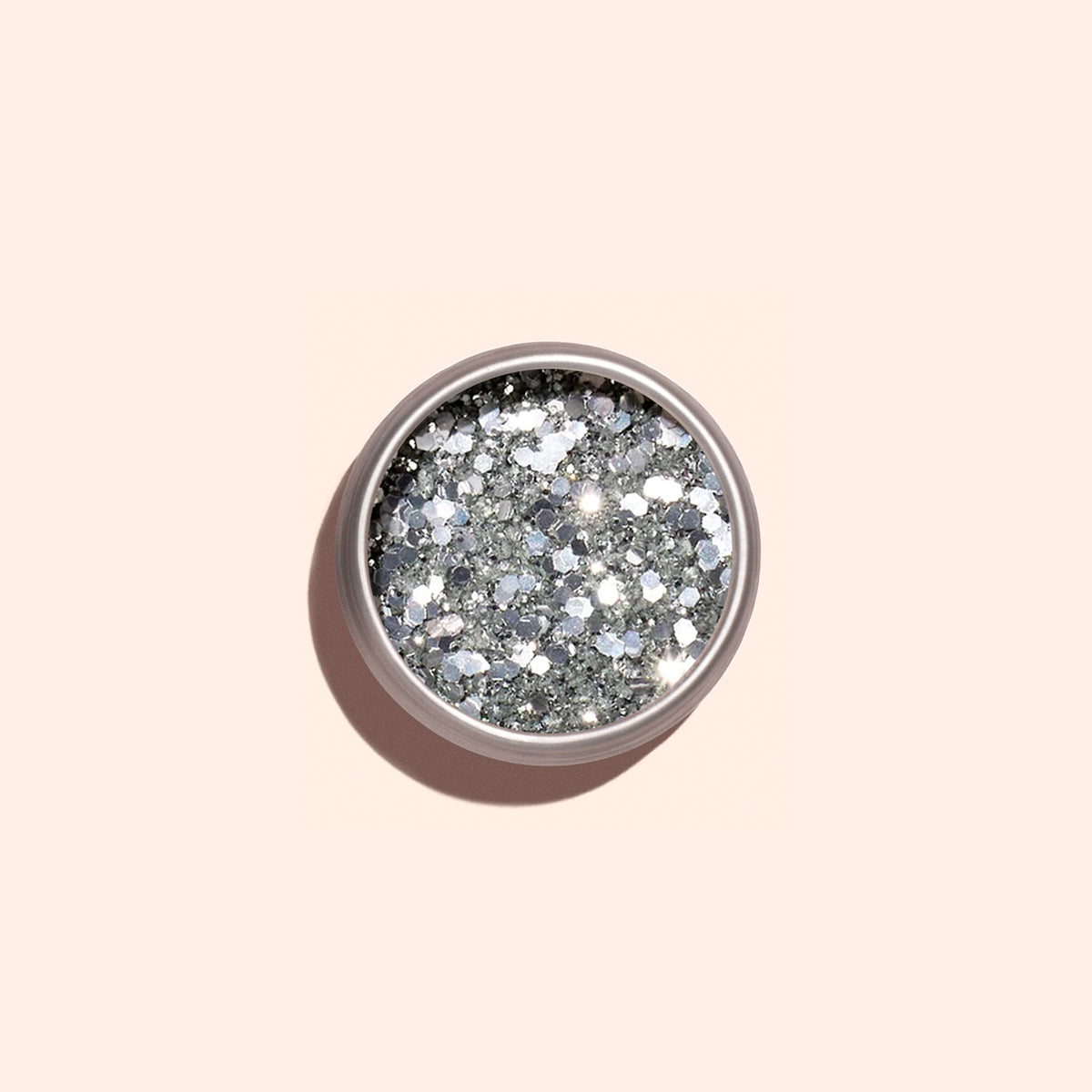 Un pot rond de paillettes biodégradables Silver Manucurist, conçu pour le nail art, repose sur un fond beige clair avec une ombre douce projetée vers la gauche.