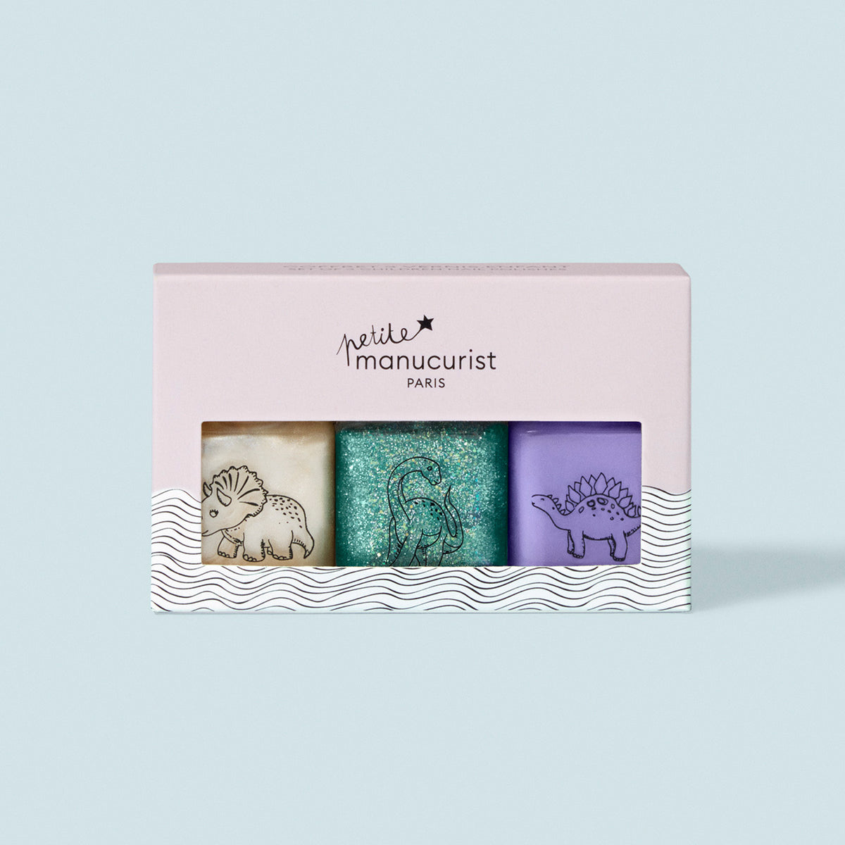 The Manucurist Wild Life Collection kids nail polish set includes three washable shades—cream, glittery teal, and purple—each with a dinosaur design, all in a pink Petite Manucurist Paris box. Gentle formula; perfect for children.