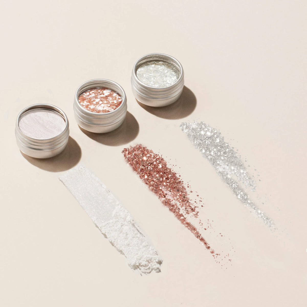 Le trio de Paillettes et Poudres à effets Manucurist comprend trois petits pots ronds en blanc, or rose et argent, chacun accompagné de son swatch assorti. Idéal pour apporter de la brillance aux ongles ou au maquillage.
