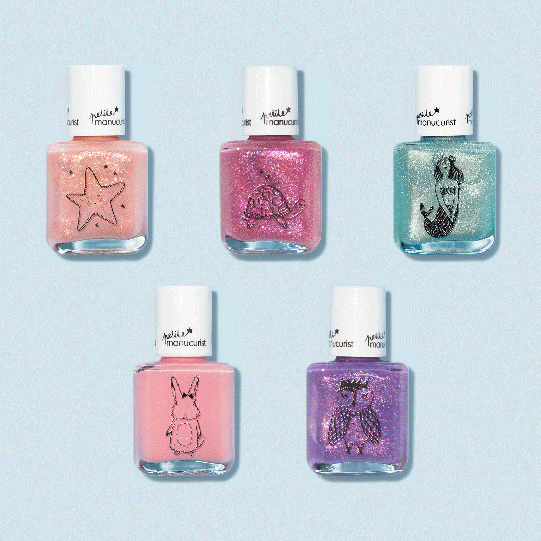 Five Customizable 5-pack Petite Manucurist nail polishes by Manucurist rest on a light blue background, each with playful black outline designs—starfish, turtle, mermaid, rabbit, and owl—a whimsical rainbow set for kids.