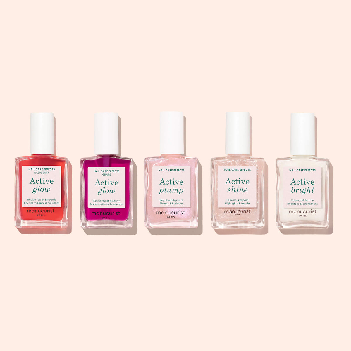 Cinq flacons de soins pour les ongles biosourcés Manucurist, comprenant Active™ Glow Raspberry, Active Plump, Active Shine et Active Bright, sont disposés en ligne sur un fond rose clair, soulignant leur engagement pour la nutrition des ongles.