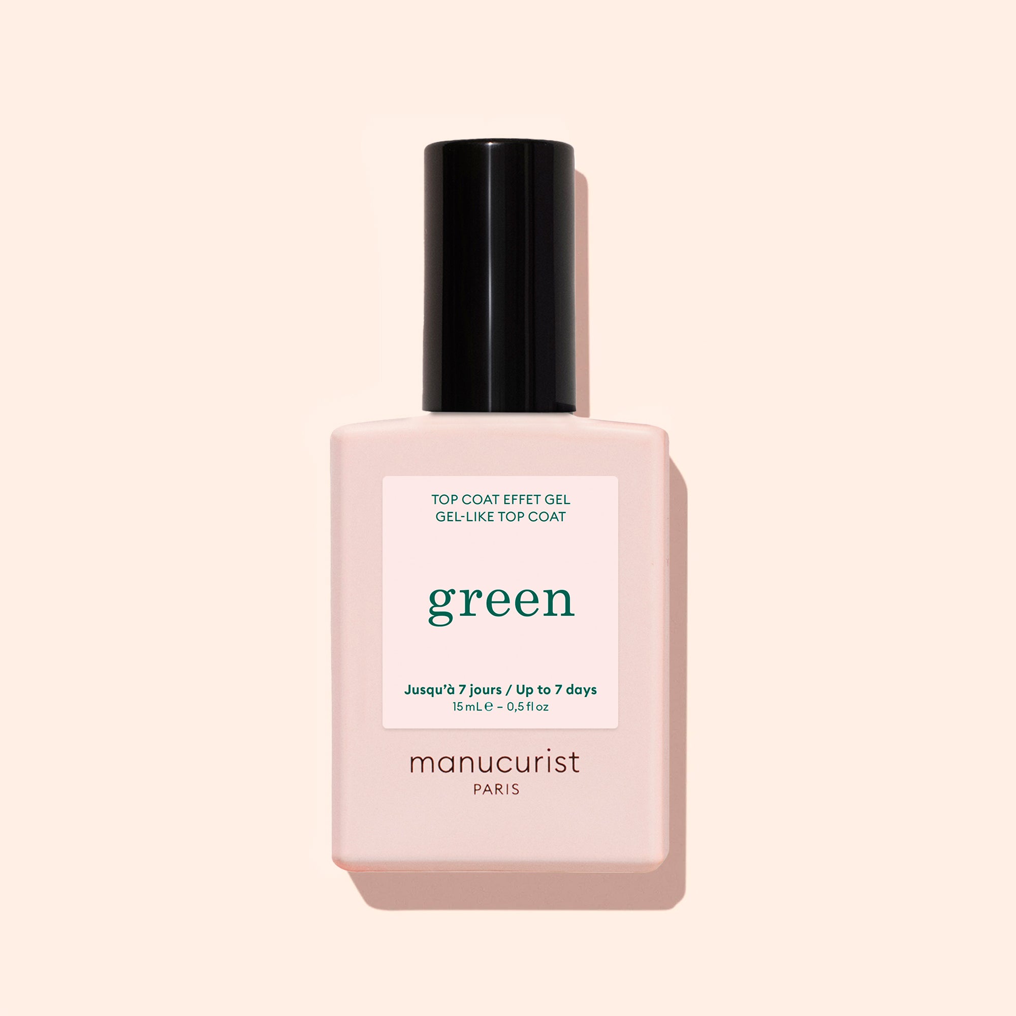 A bottle of Manucurist Green Sunshine Top Coat comes in a pale pink rectangular bottle with a black cap and white label, offering a gel-effect finish with its plant-based formula.