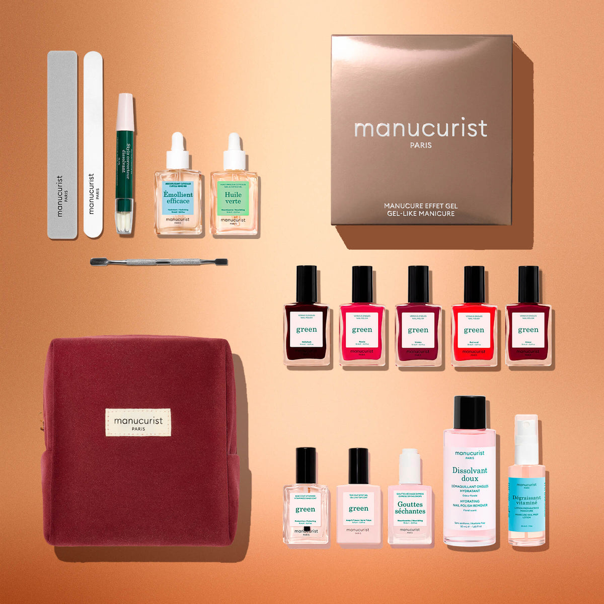 A flat lay of the Manucurist Green™ Super Ultimate Kit Gift Set, featuring files, a cuticle tool, nourishing oils, seven naturally derived nail polishes, remover, topcoat, nail drops, and a red pouch—all neatly arranged on a peach background.