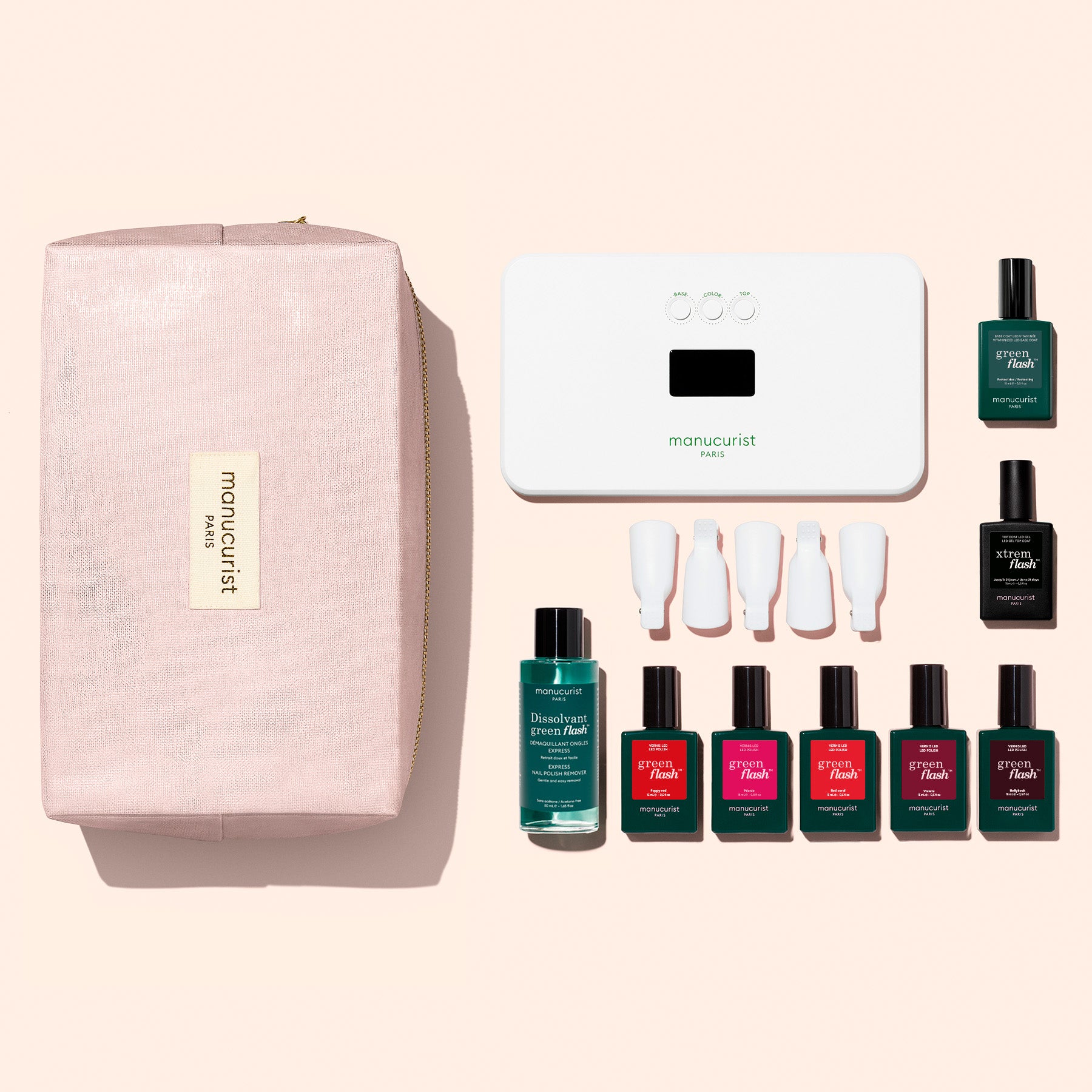 The Manucurist Super Starter Kit, arranged neatly on a light background, includes a pink pouch, UV lamp, nail polish remover, four polishes with white caps, plus two top/base coats—providing everything you need for an ultra-glossy manicure at home.