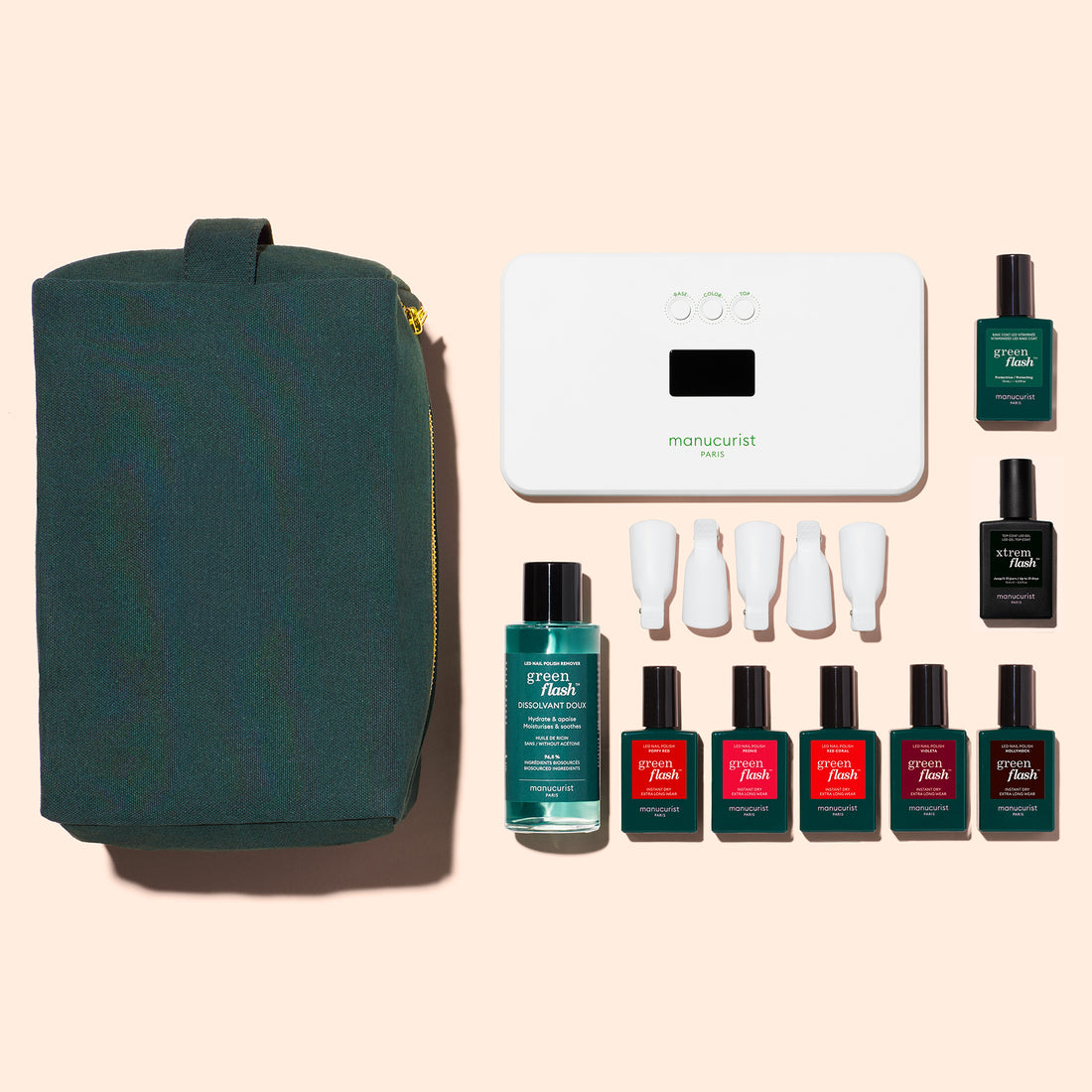 The Manucurist Super Starter Kit includes a green zippered pouch, white LED nail lamp, six gel polish bottles in assorted colors, remover, and four white nail tools, all neatly arranged on a light beige background.
