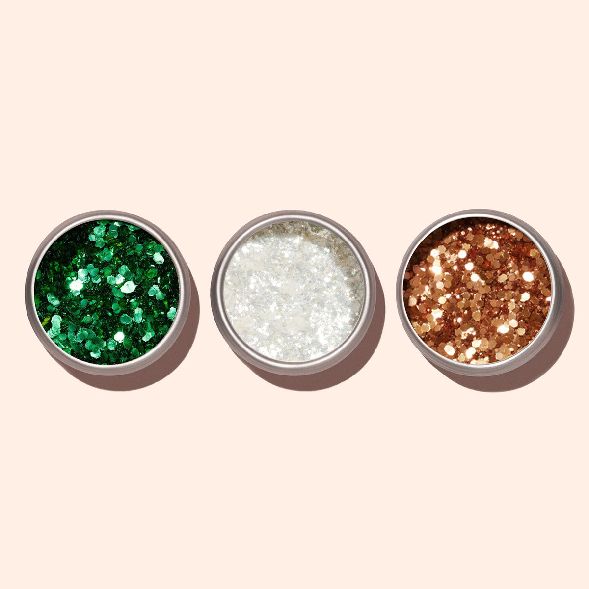 Trois pots métalliques ronds de Paillettes Biodégradables Copper Manucurist sont disposés côte à côte sur un fond beige clair. Les paillettes vertes, blanches et dorées sont parfaites pour le Nail Art.